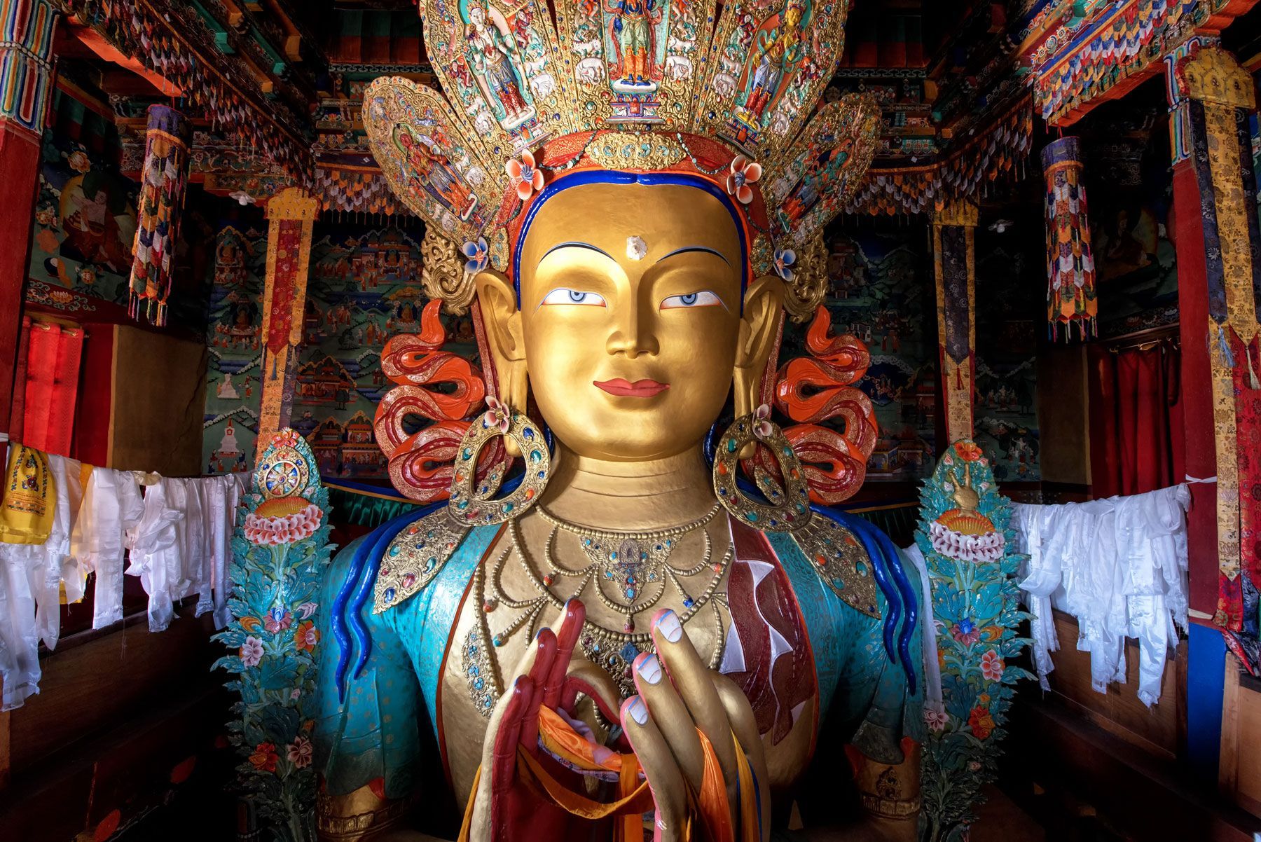 Golden Buddha statue in ornate temple with colorful decorations.