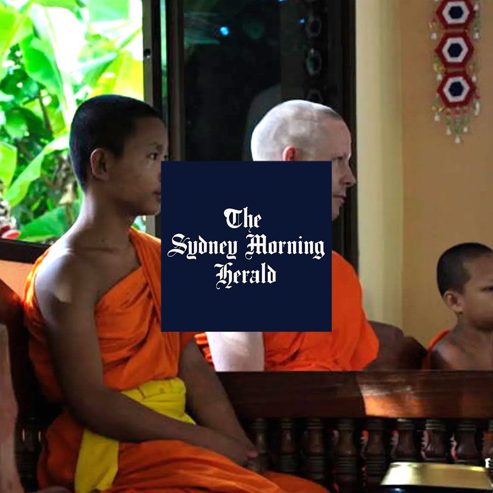 Young Buddhist monks in orange robes seated in a temple.
