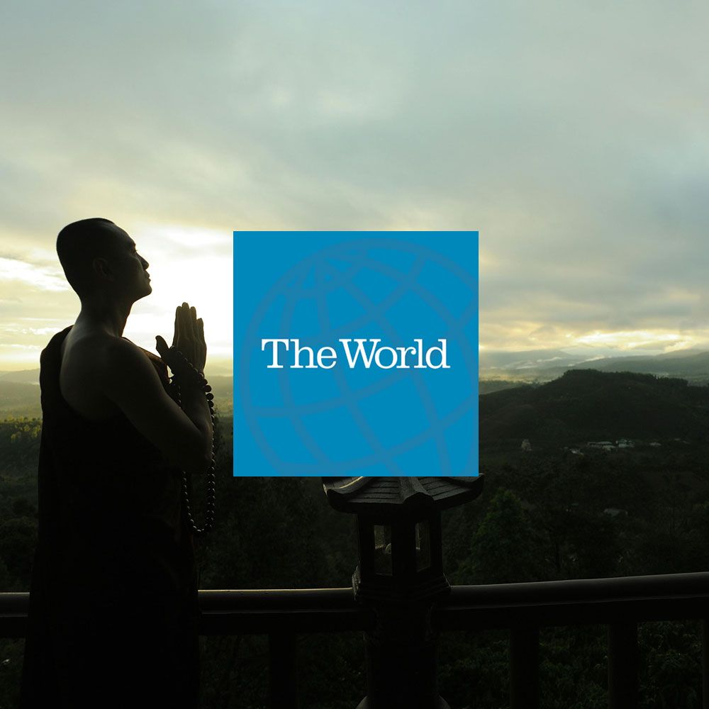 Silhouette of a monk with hands clasped in prayer, facing the sky, in front of a blue square with