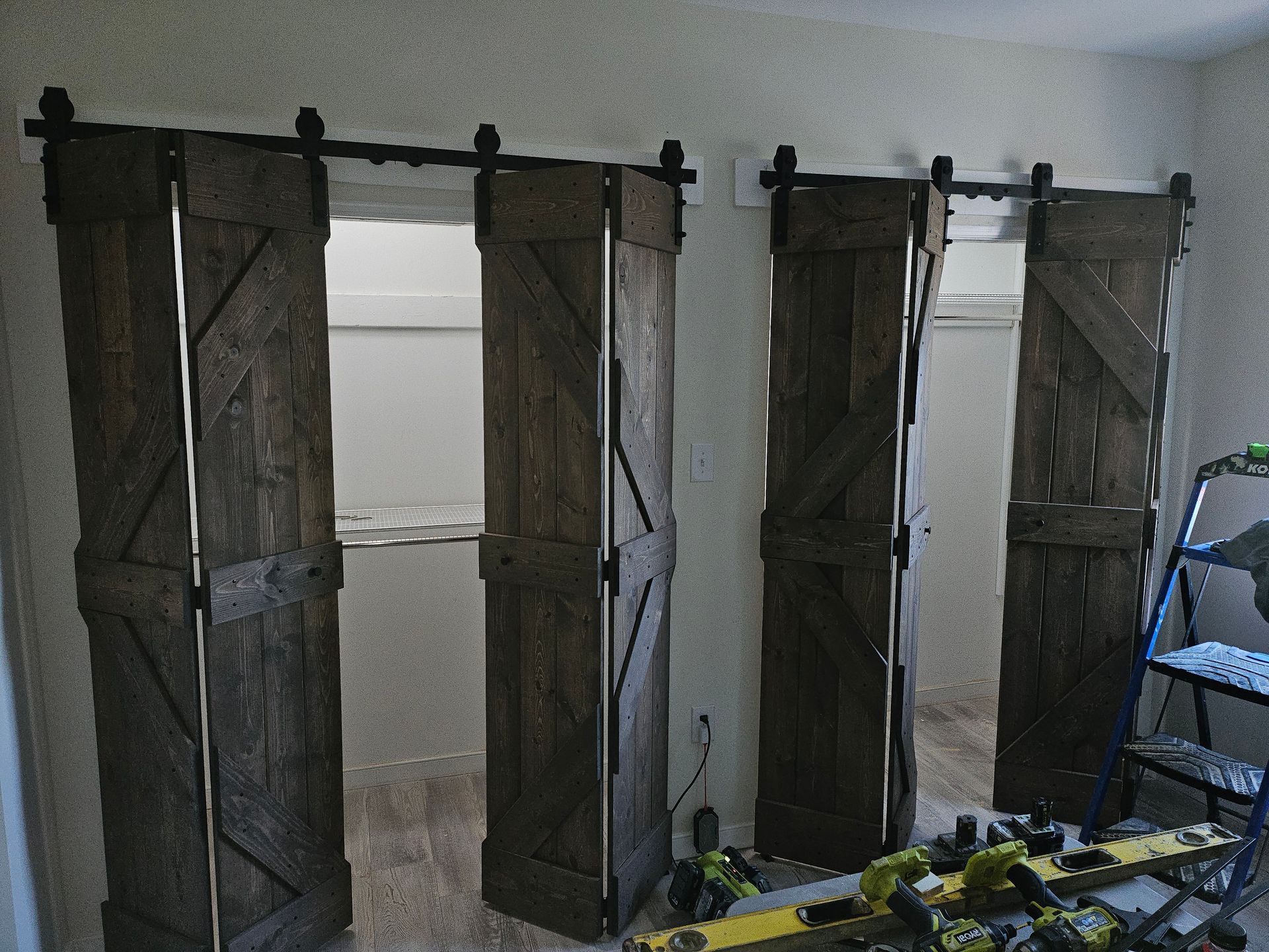 Barn-style sliding doors, weathered brown, on a track. Open over a window, tools on the floor.