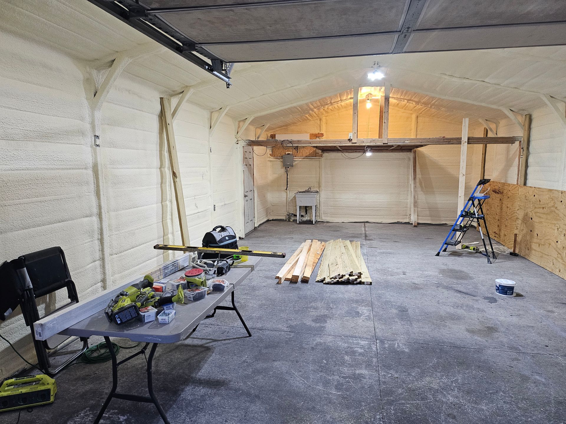 Interior of a garage with exposed wooden beams and tools on a table, ready for construction.