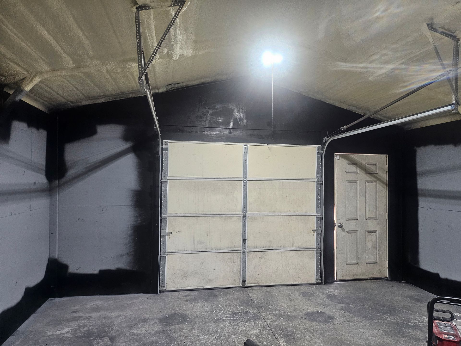 Garage interior with black painted walls and a white garage door.