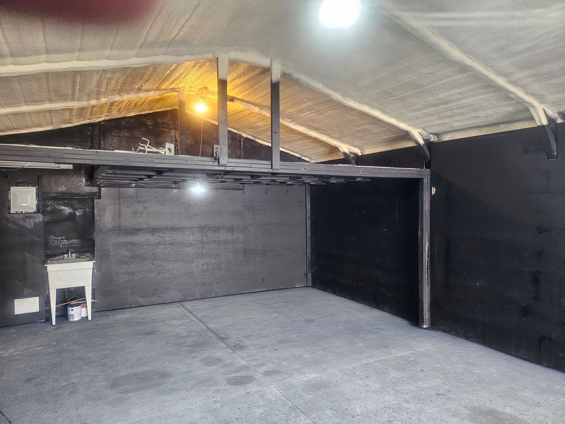 Indoor space with black walls, white ceiling, and a small shelf.