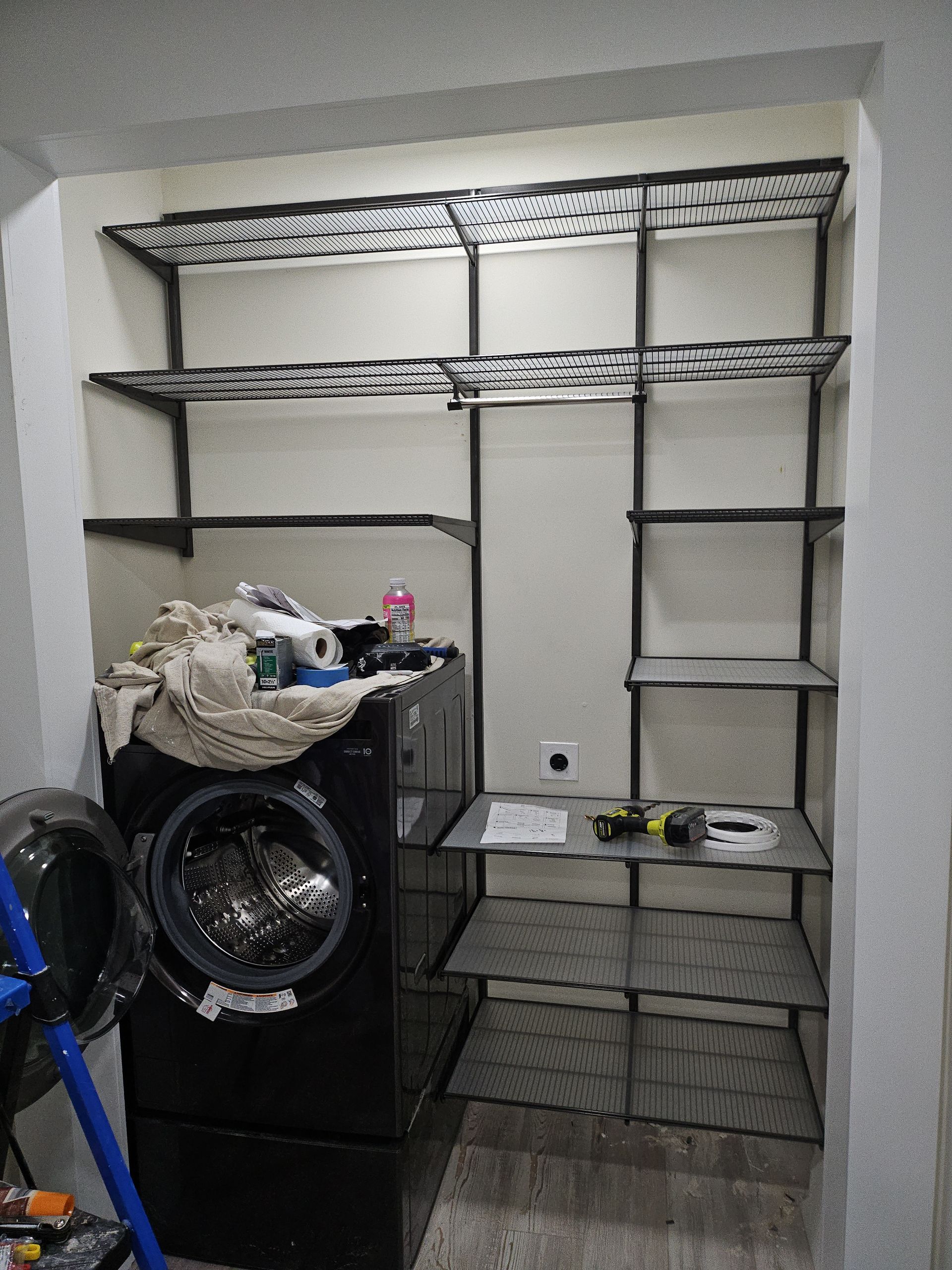 Laundry room with black washing machine and wire shelving.