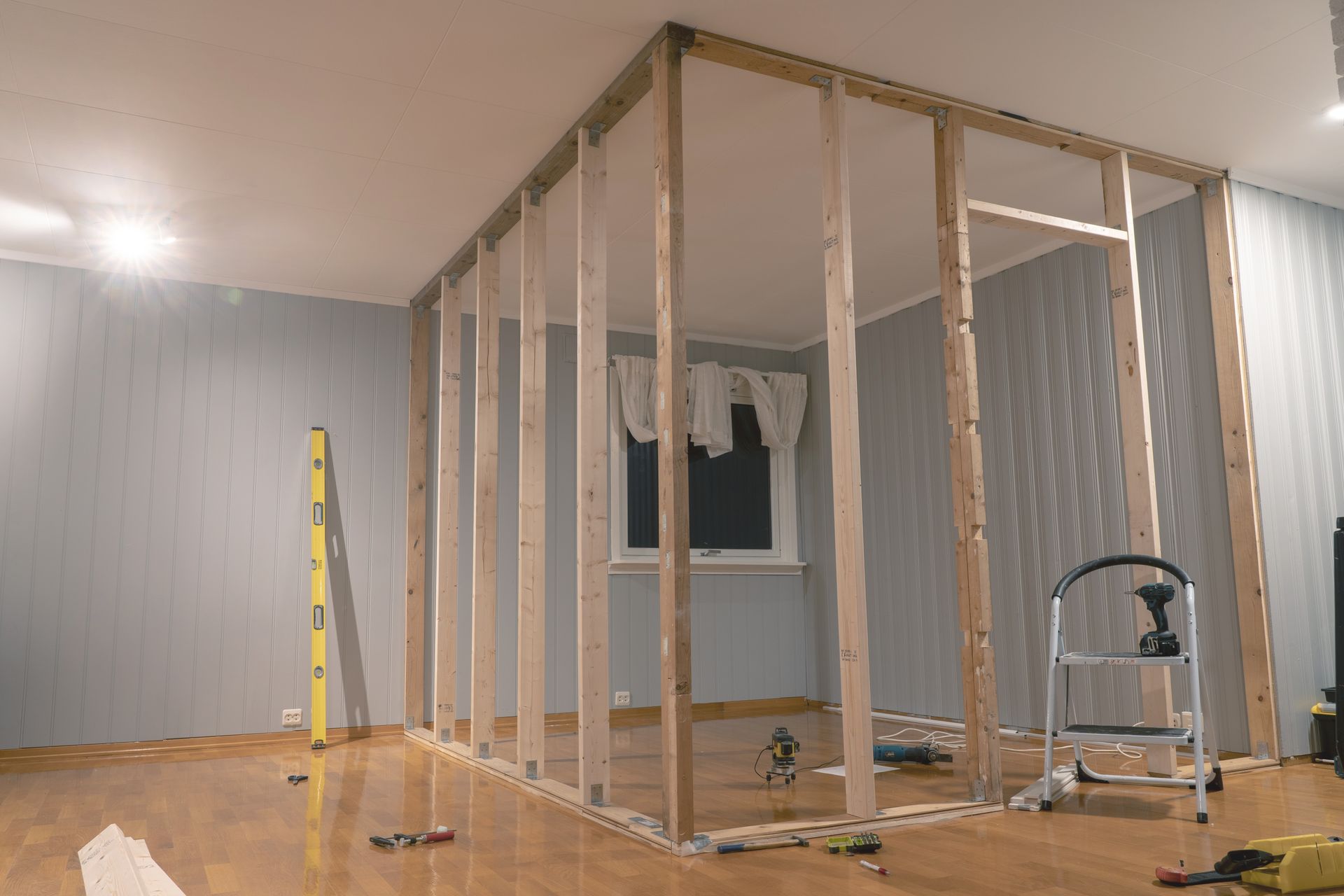Partially framed interior room under construction with drywall, exposed studs, and tools on the floor