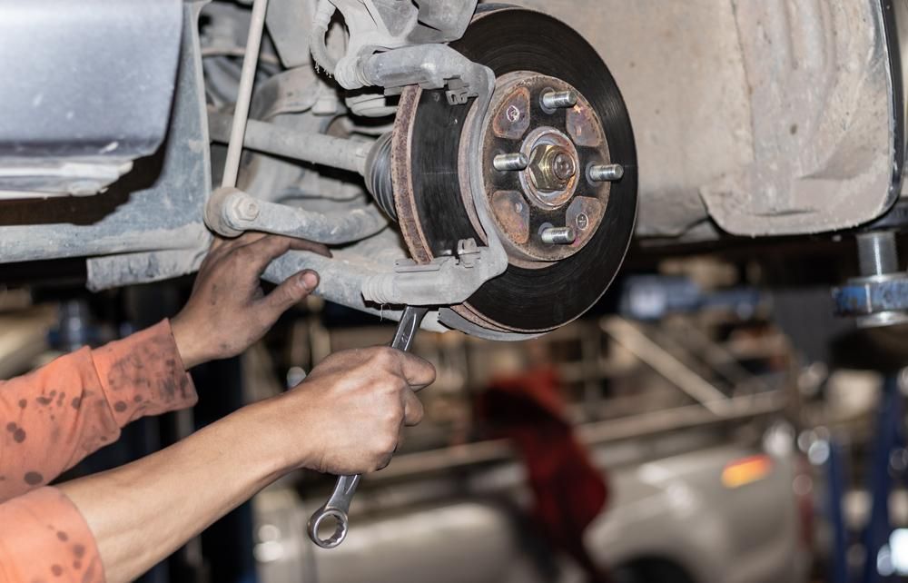 A Man Is Working On A Car With A Wrench — Mechanic in Lismore, NSW