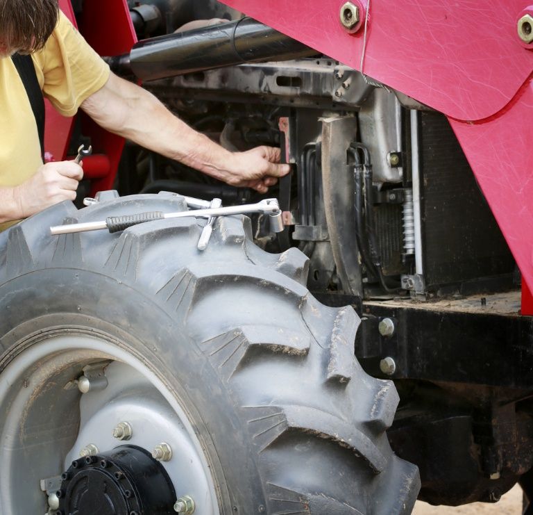 A Man in a Yellow Shirt is Working on a Red Tractor — Burmec In Narrabri, NSW