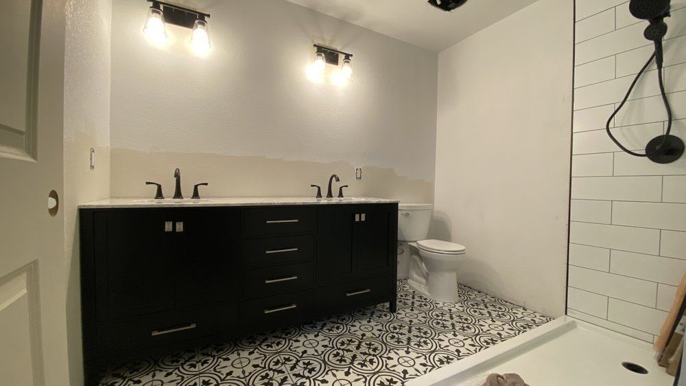 Modern black double vanity bathroom with patterned tile floor and glass shower enclosure
