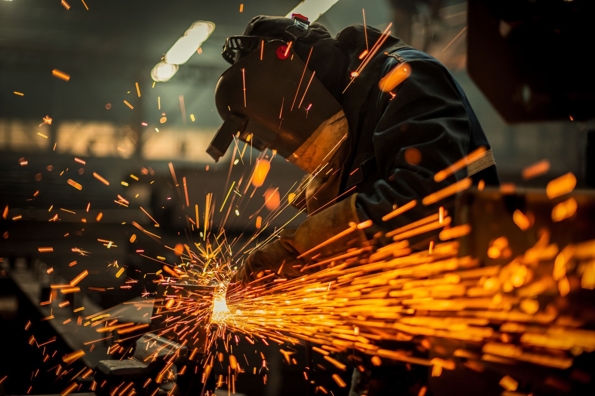 A man is welding a piece of metal in a factory.