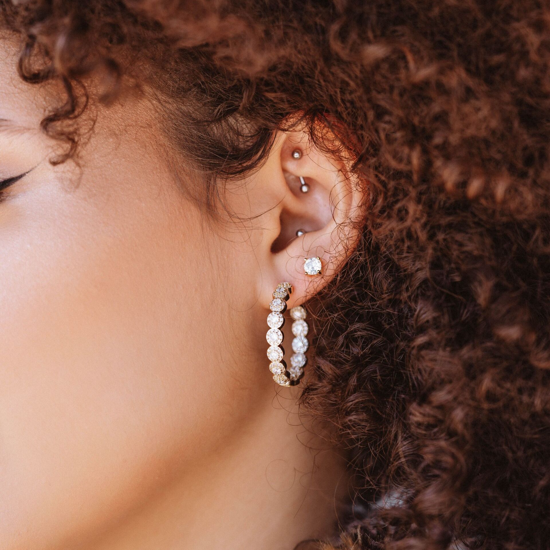 A close up of a woman 's ear with hoop earrings and piercings.