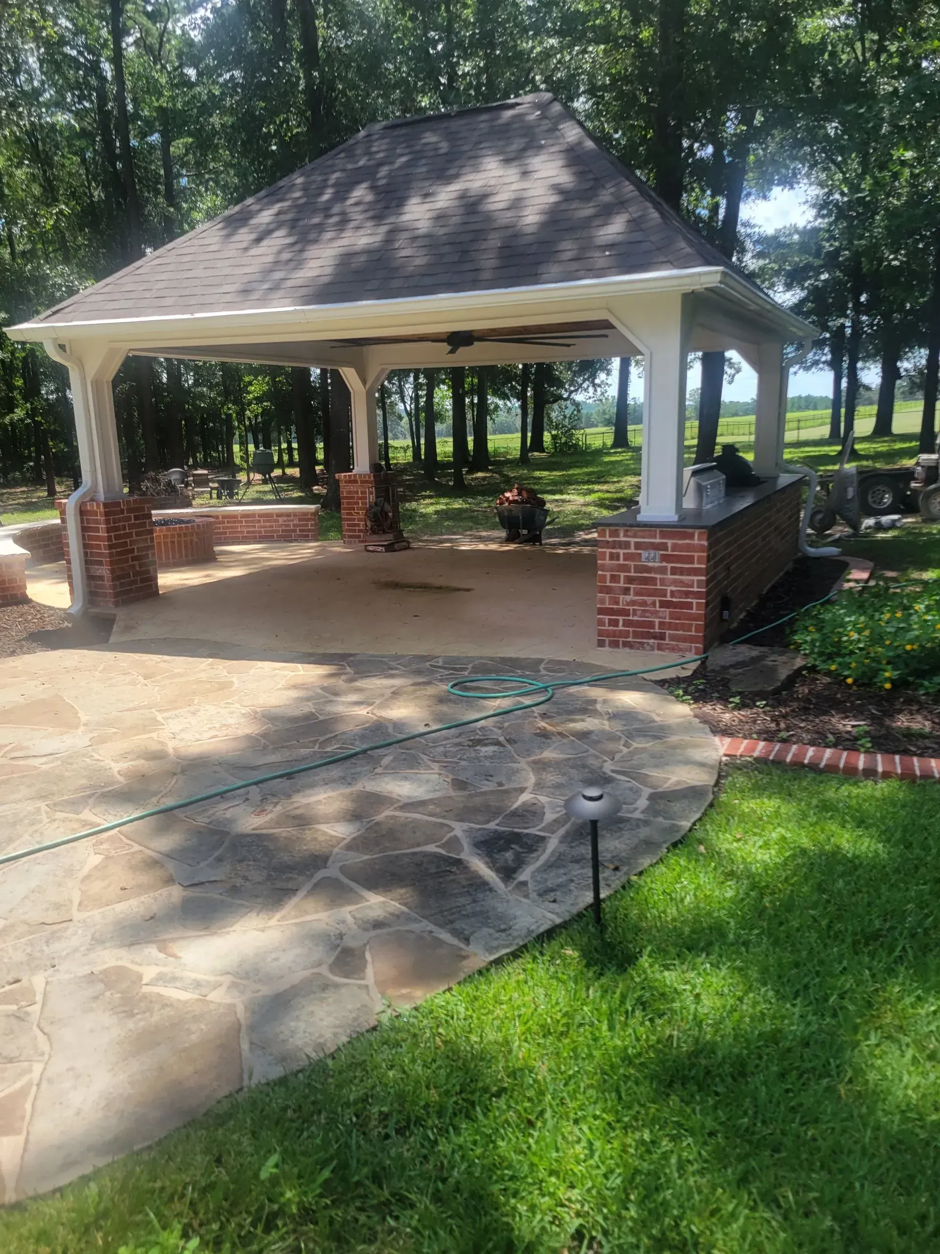 A gazebo is sitting in the middle of a lush green field.