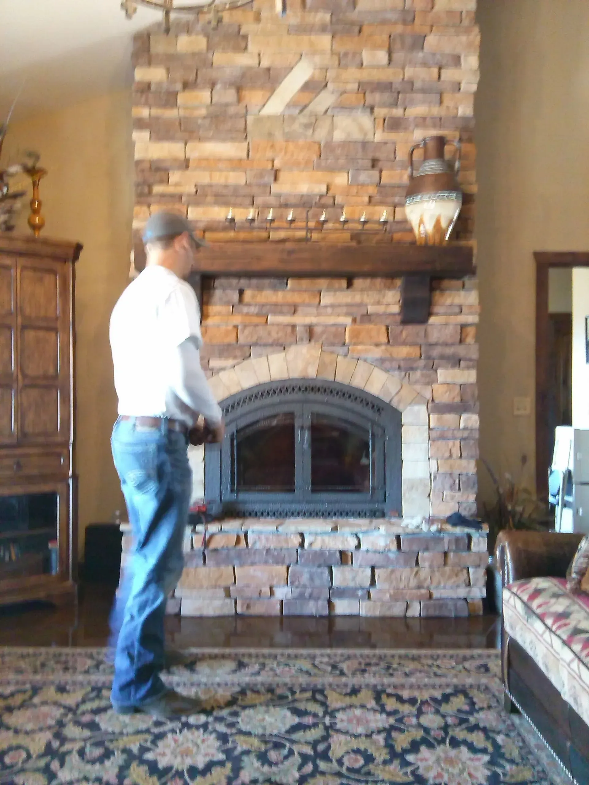 A man standing in front of a brick fireplace in a living room