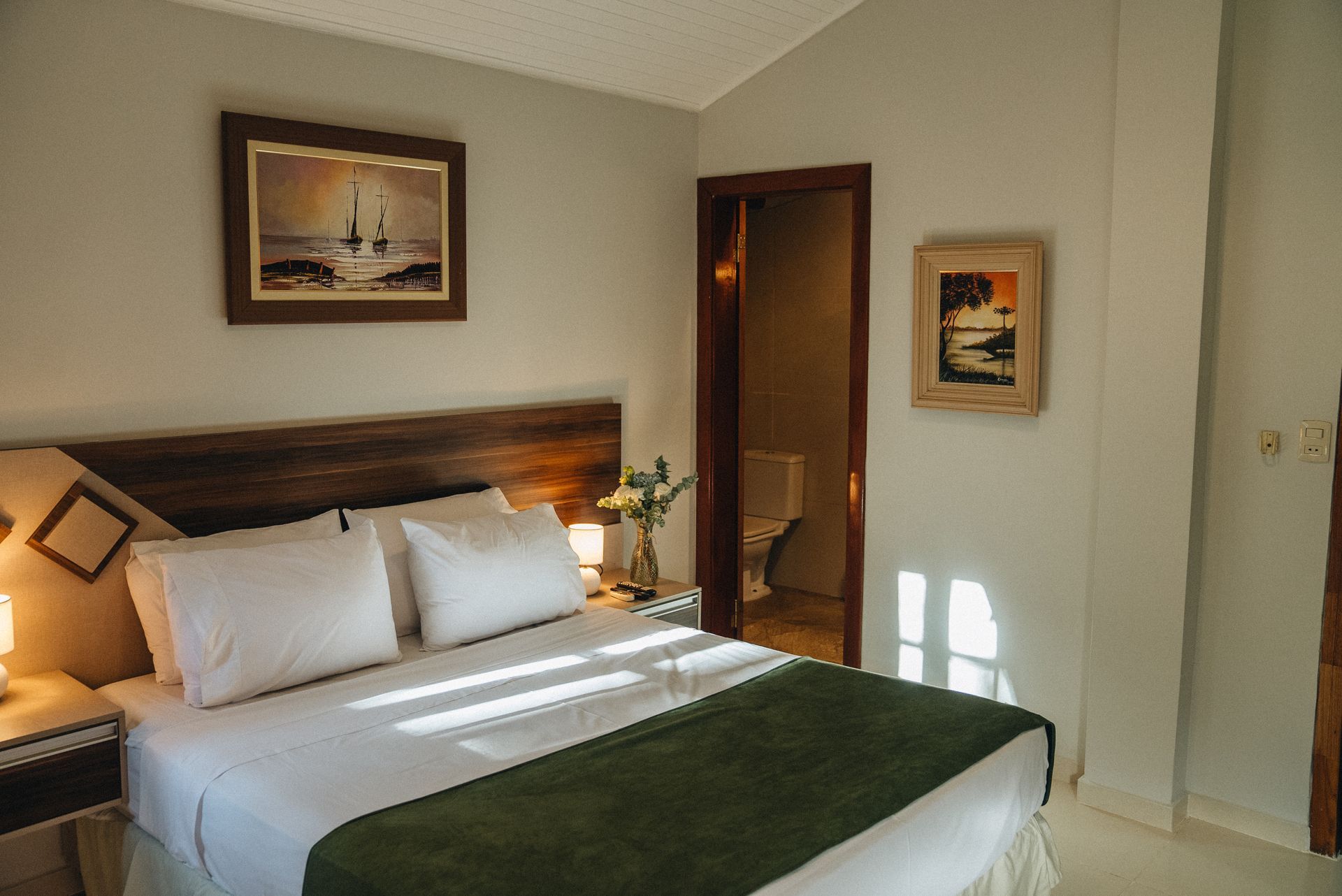 Un camino de tierra que conduce a una casa rodeada de árboles y arbustos.