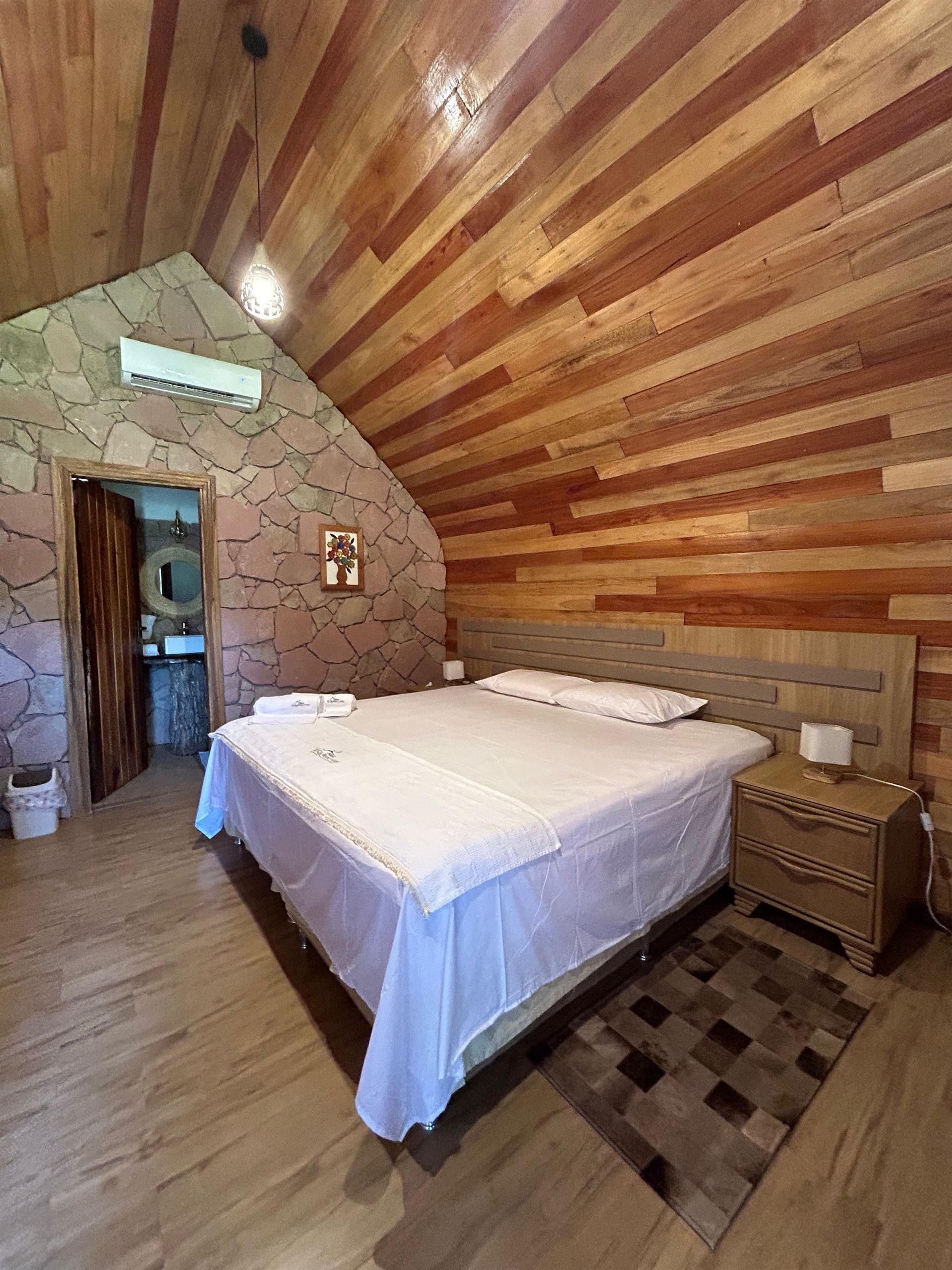 Un dormitorio con cama, mesita de noche y paredes de madera.