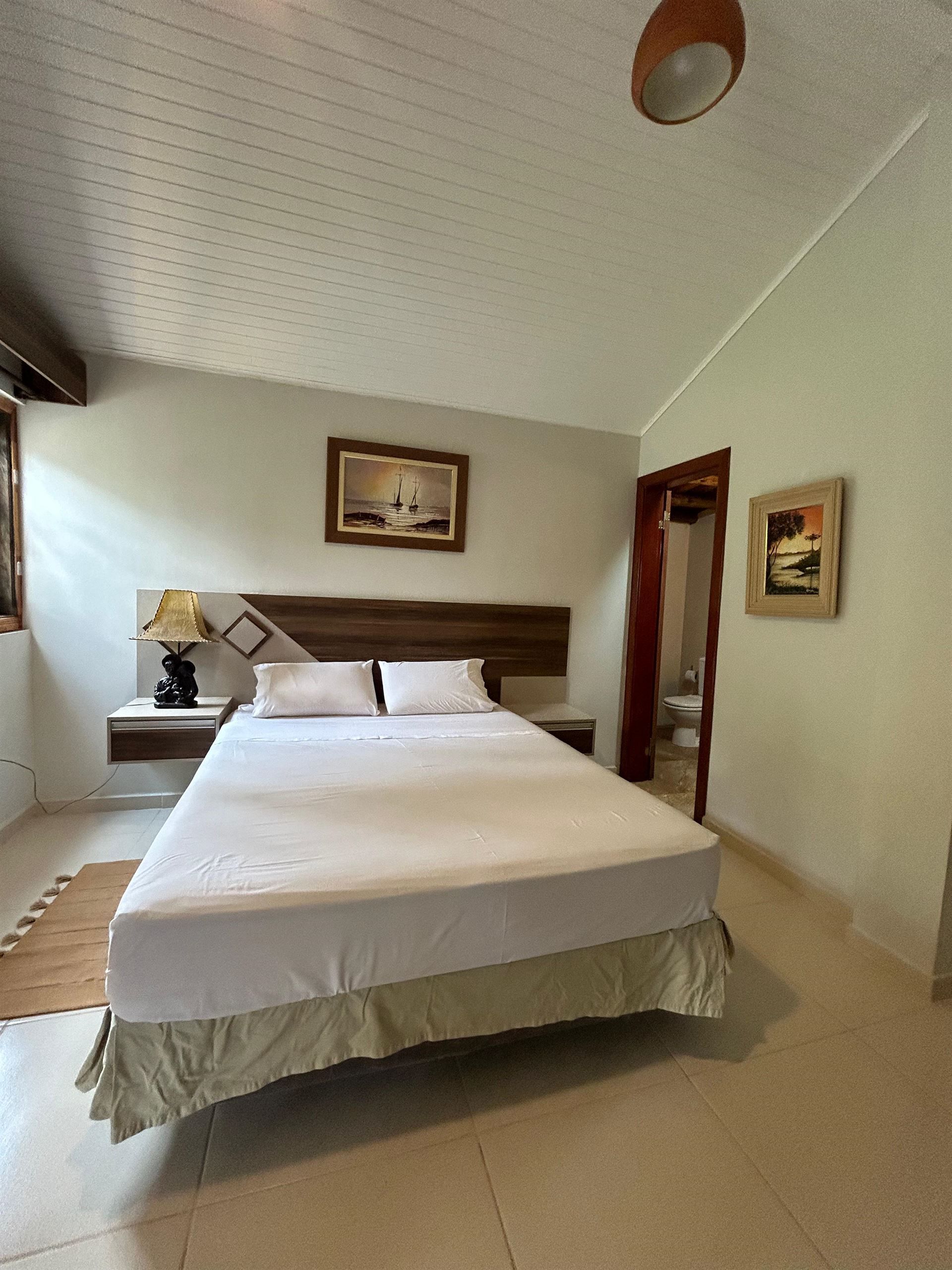 Un dormitorio con una cama grande y una lámpara en la mesita de noche.