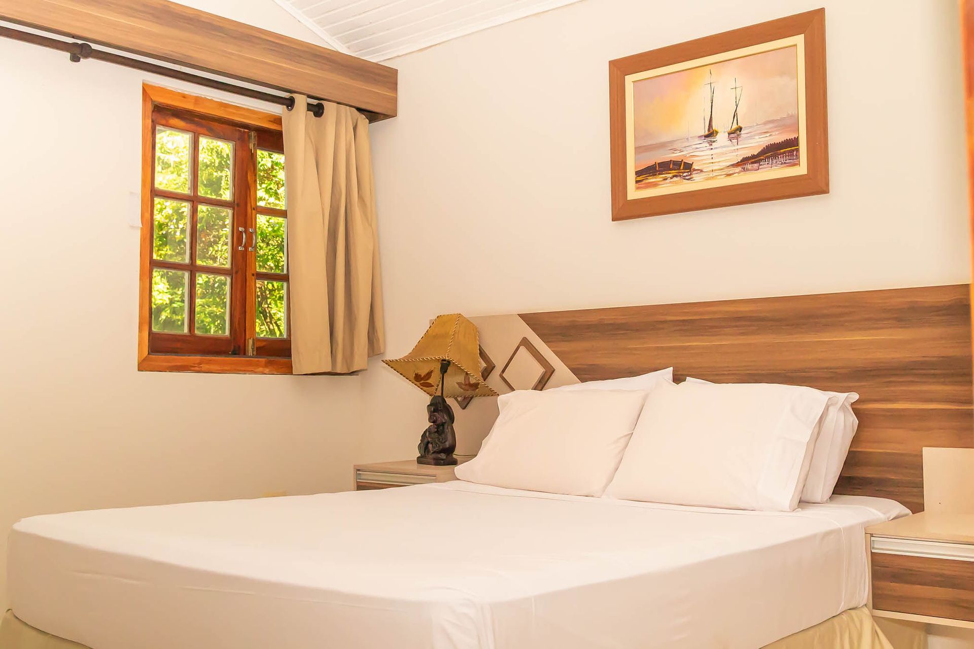 Un camino de tierra que conduce a una casa rodeada de árboles y arbustos.