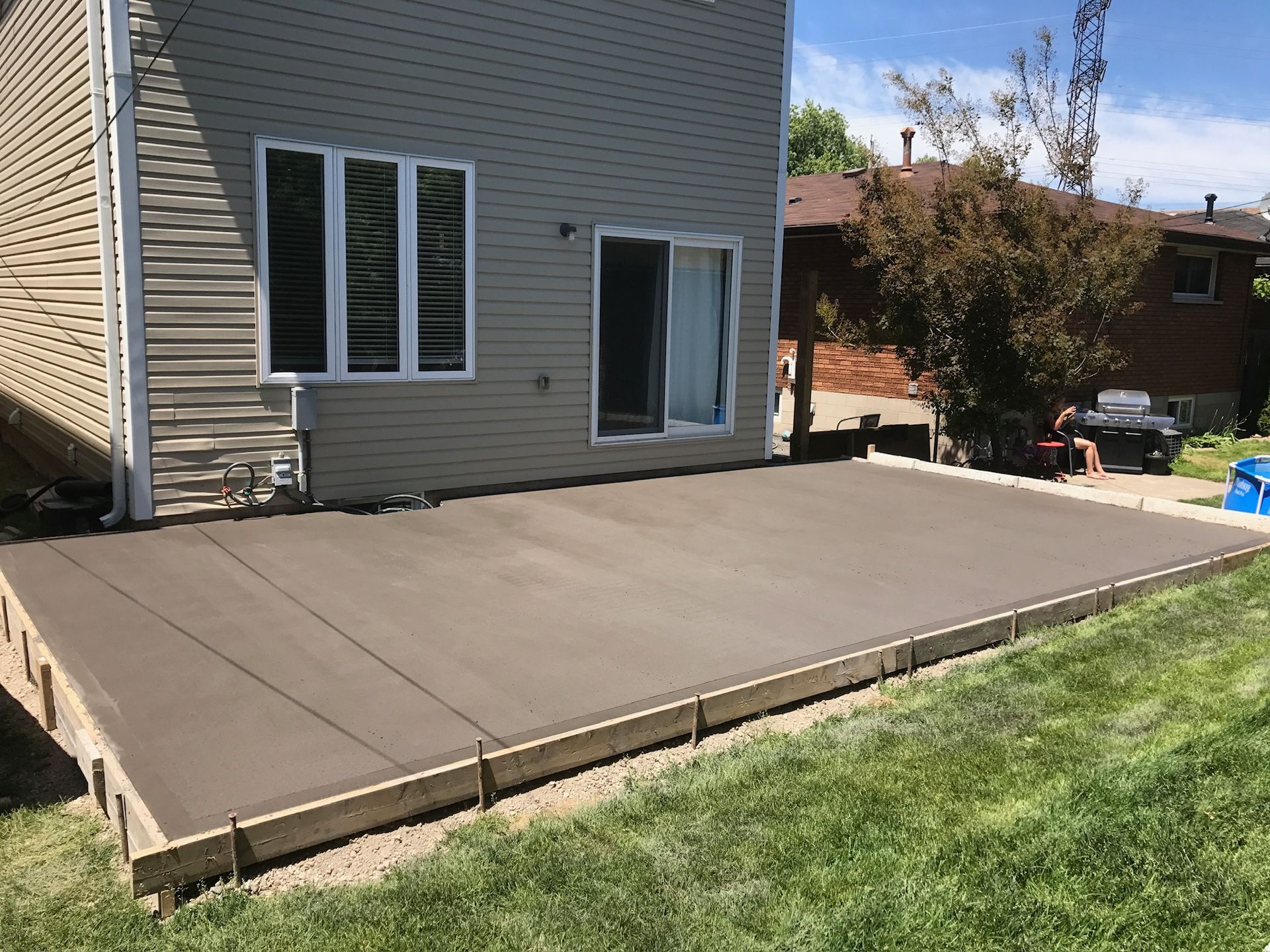 A concrete deck is being built in the backyard of a house.