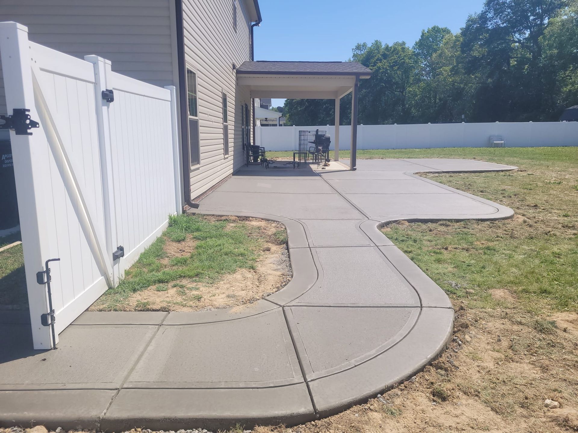 brush finished concrete walkway leading to concrete patio in back yard of home