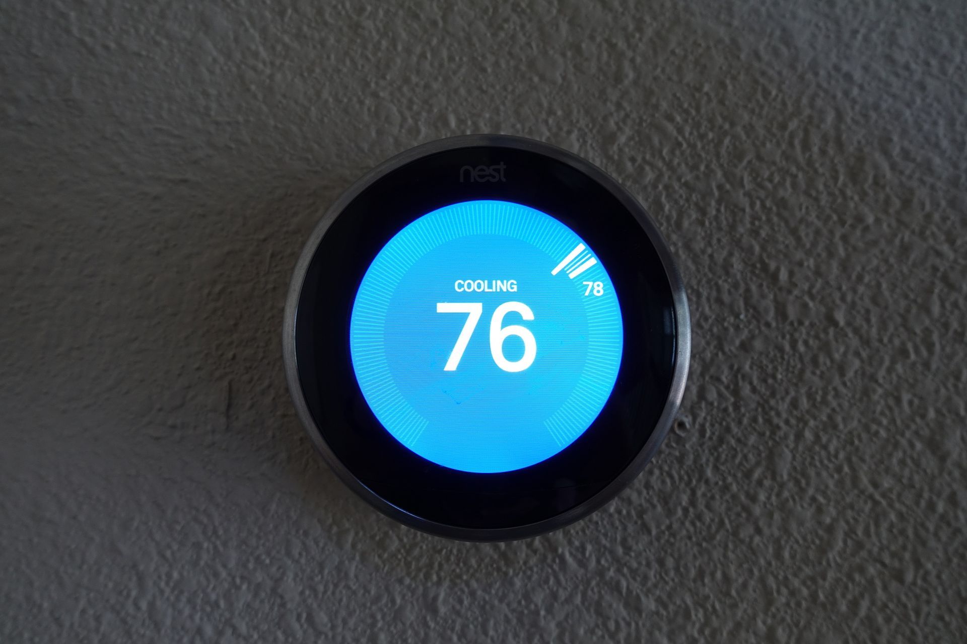 A smart thermostat is displaying the temperature as 76 degrees fahrenheit.