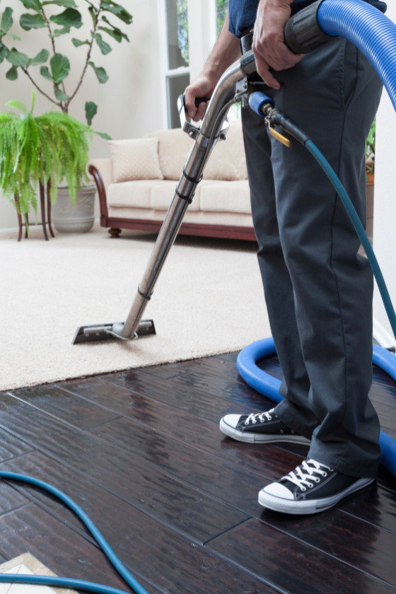 A man is using a vacuum cleaner to clean a carpet in a living room.