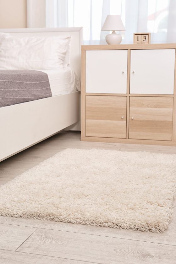 A bedroom with a bed , nightstand , and rug.