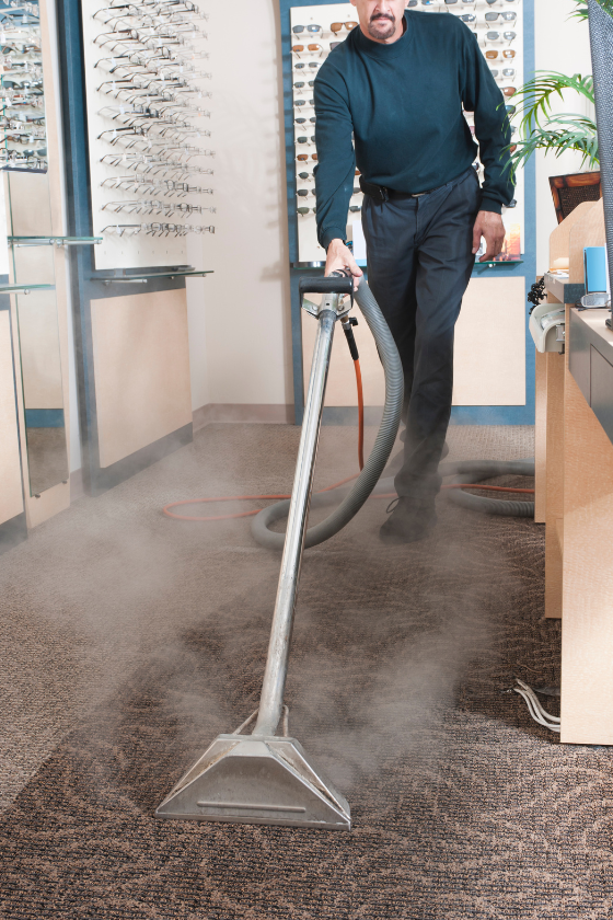 A man is using a vacuum cleaner to clean a carpet in an office.