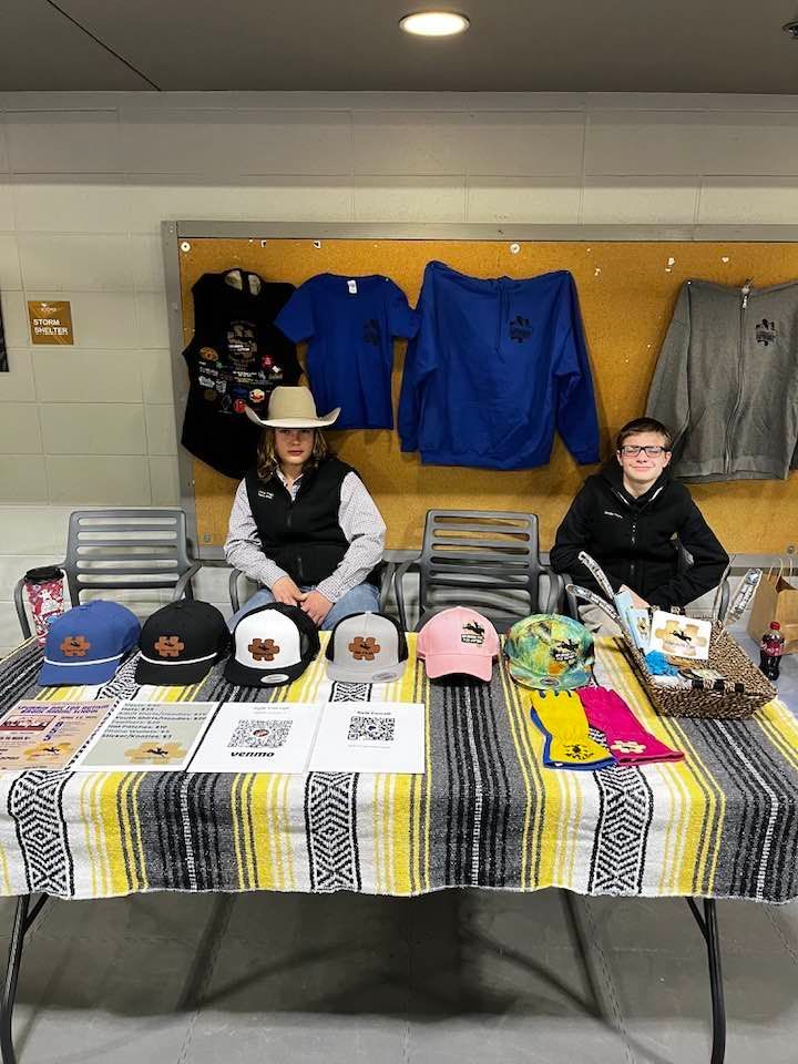 Two people are sitting at a table with hats and shirts on it.