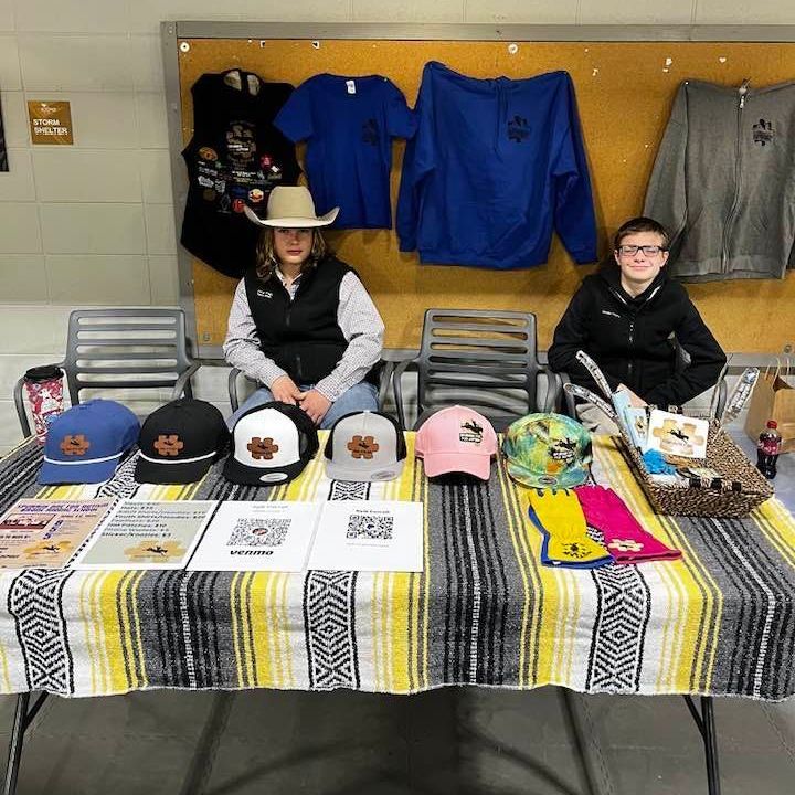 Two people are sitting at a table with hats and shirts on it.