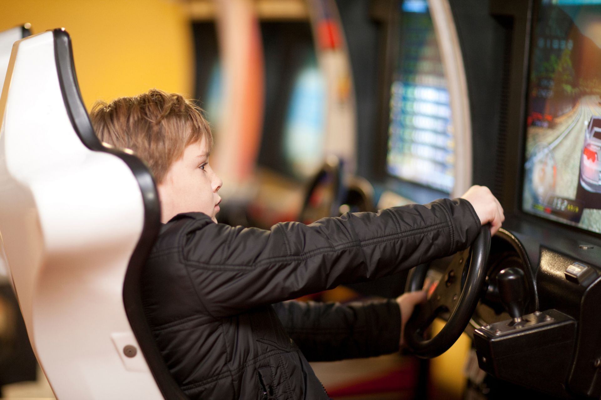 A young boy is playing a video game in an arcade.