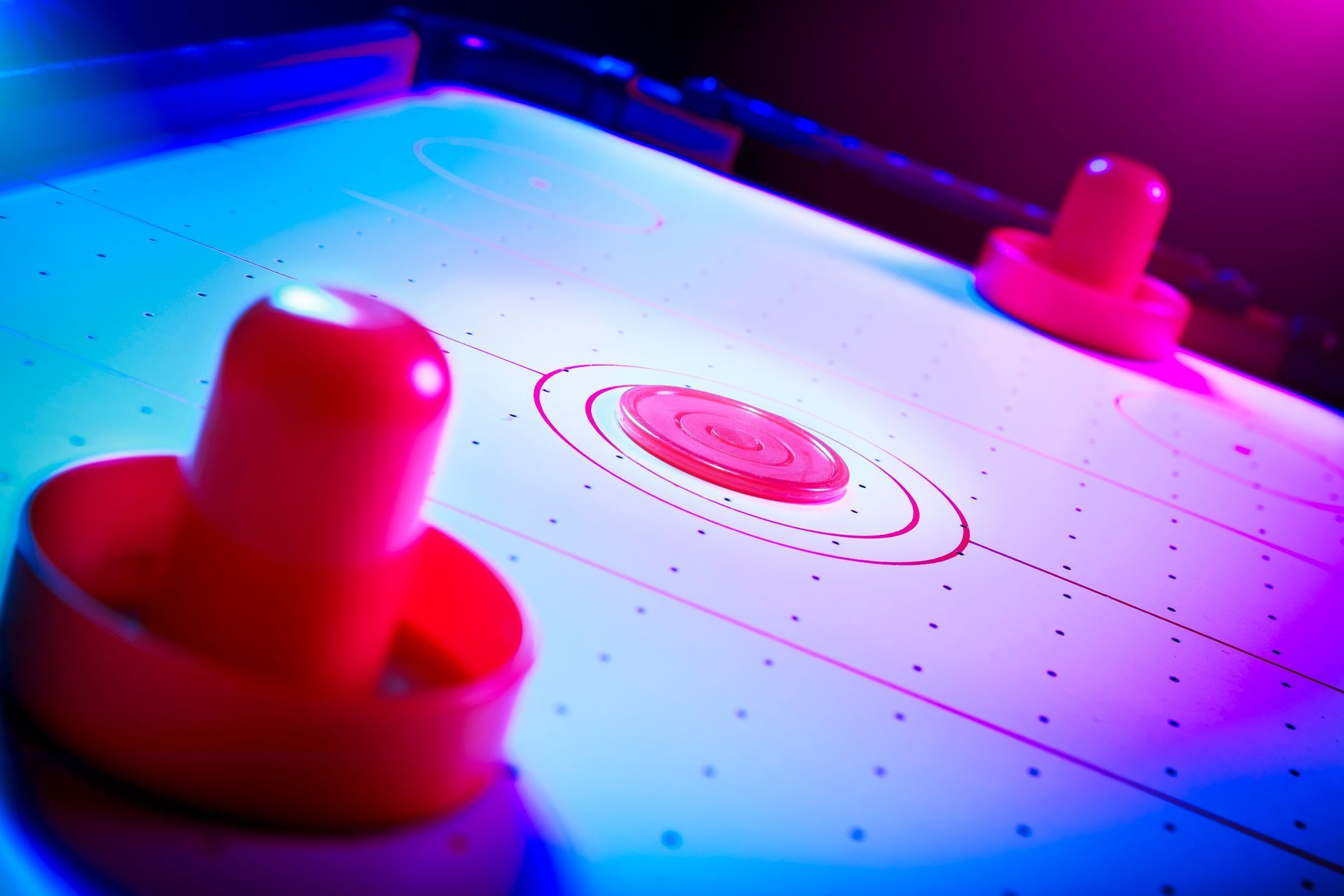 A close up of an air hockey table with two pucks on it.