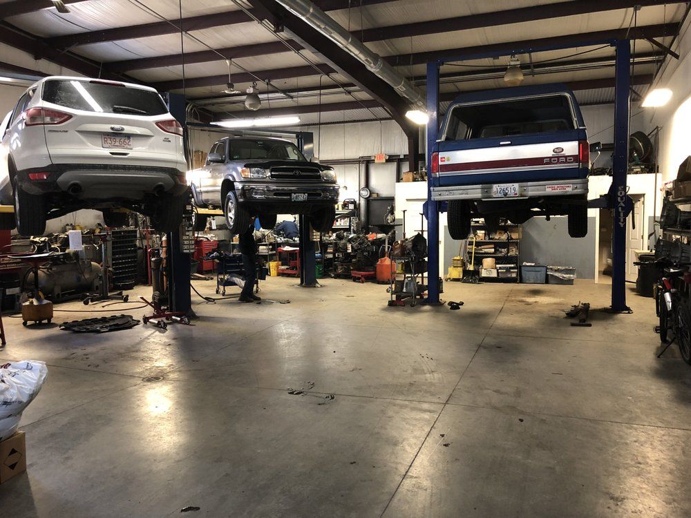 Two cars are sitting on a lift in a garage  | Franklin Transmission and Auto Care