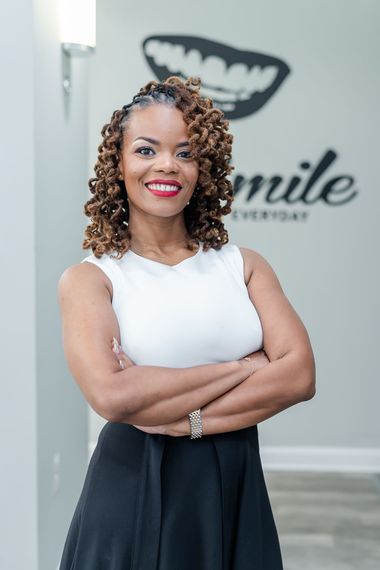 Dr. Rasheeda Johnson standing in a bright office hallway review information together on a tablet. stands with arms crossed.