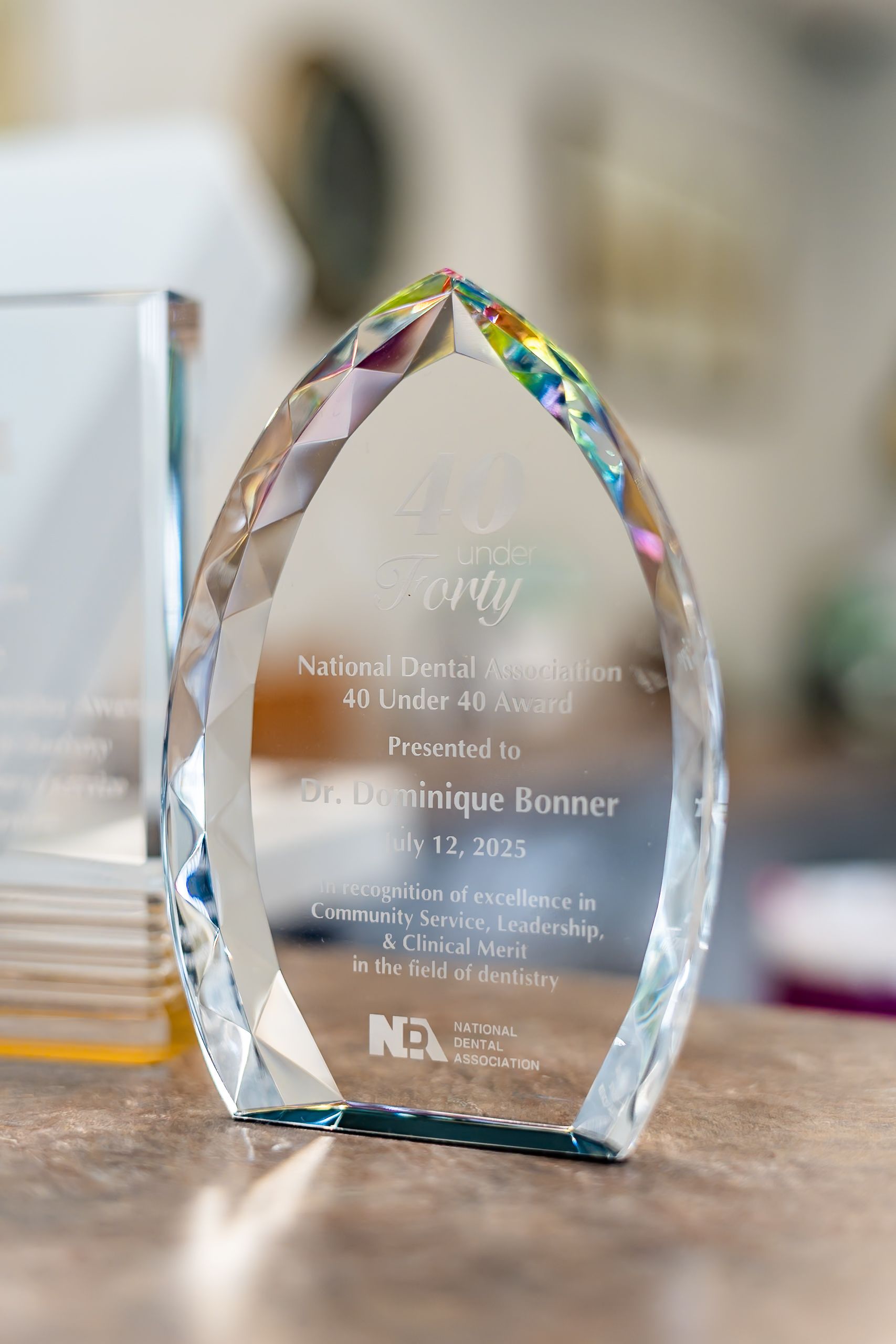 An awards trophy with the name Dr. Dominique Bonner and the date July 17, 2021 engraved on the glass surface.