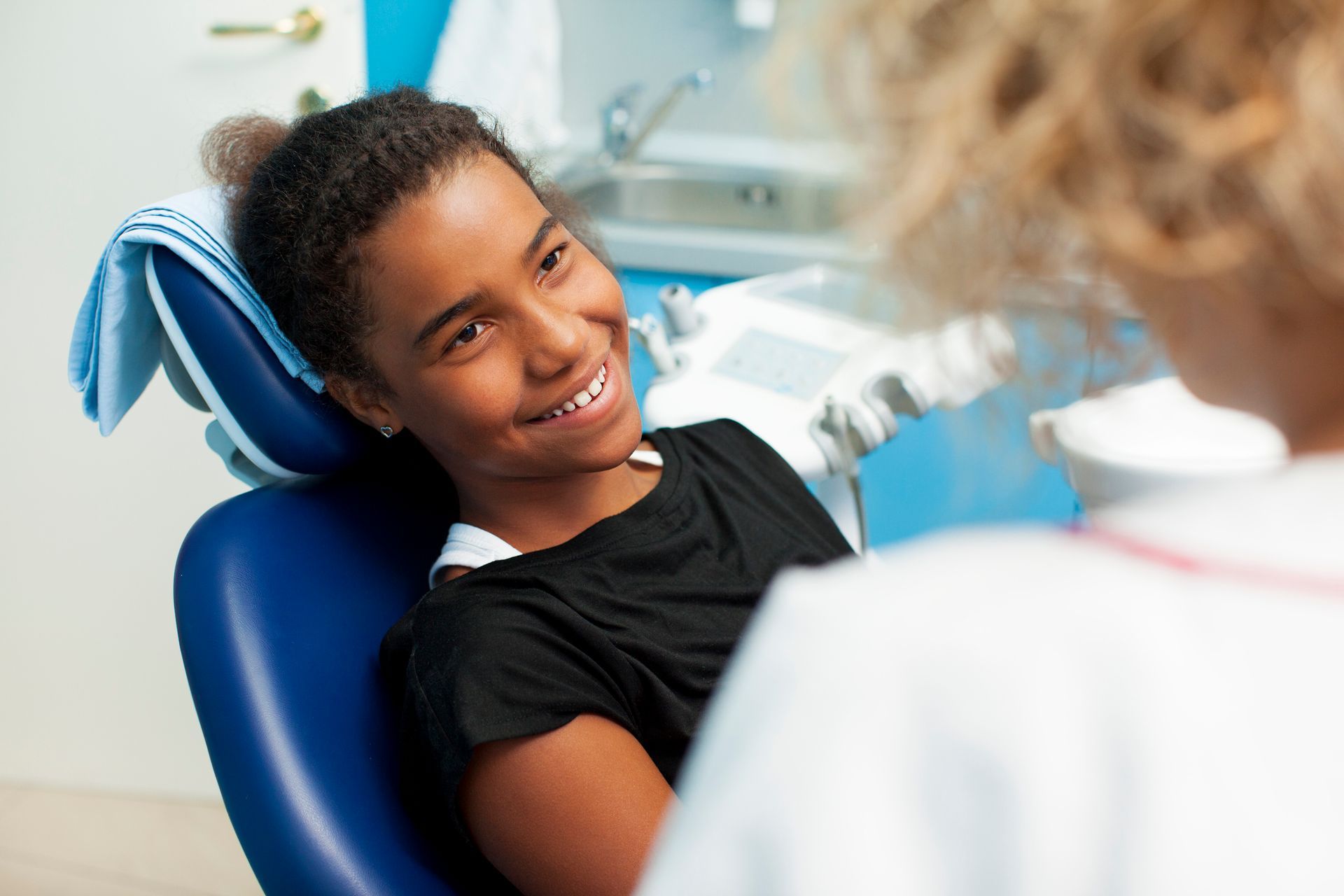 Young Black girl smiles at dentist in a dental office.
