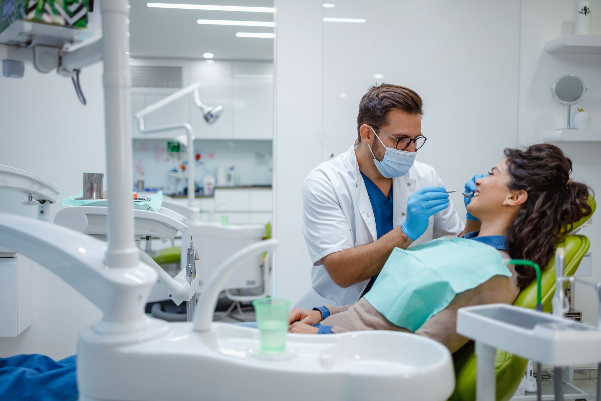 Dentist examining a woman's teeth in a bright, modern dental office. Both are focused.