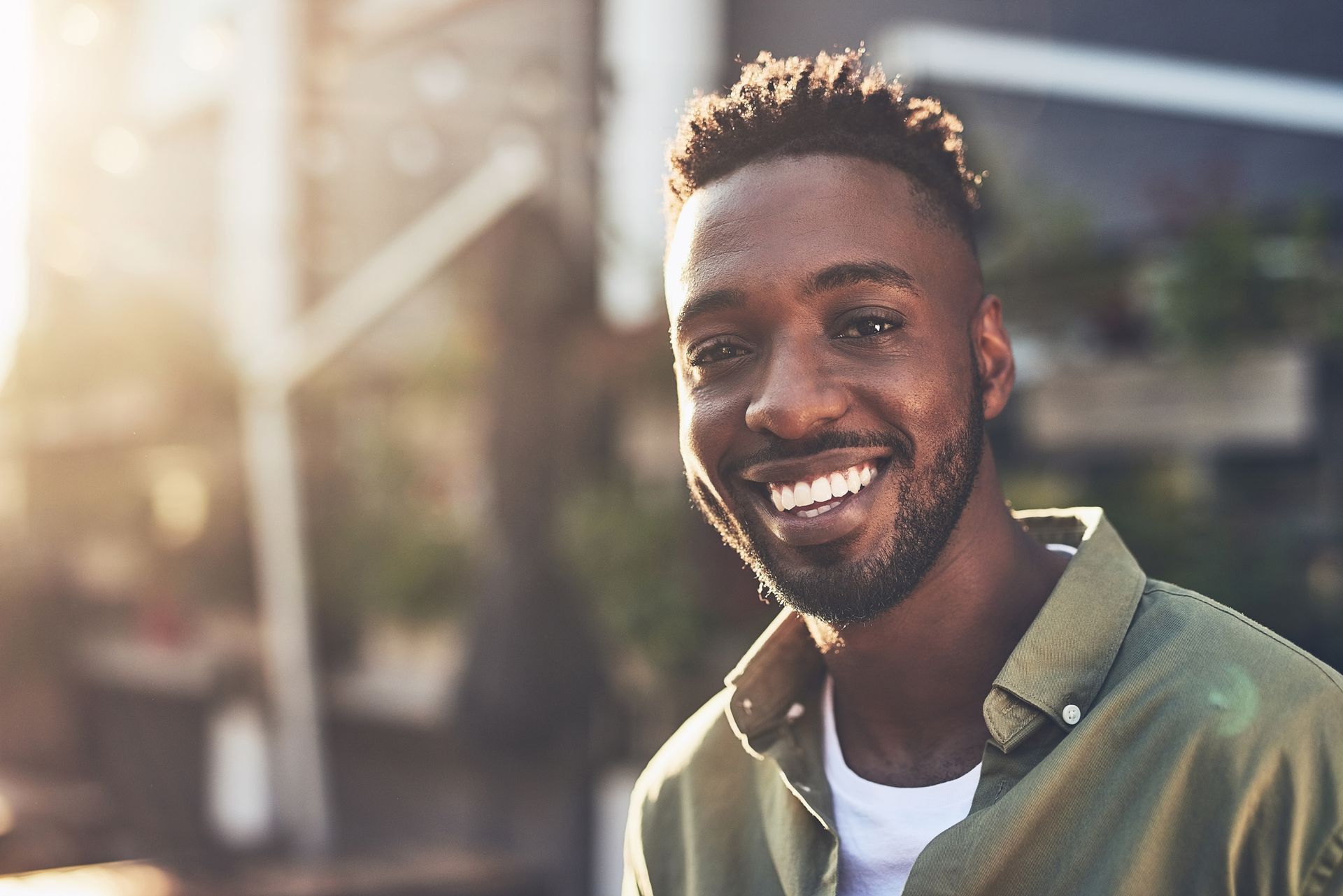 Smiling Black man outdoors, wearing a green shirt.