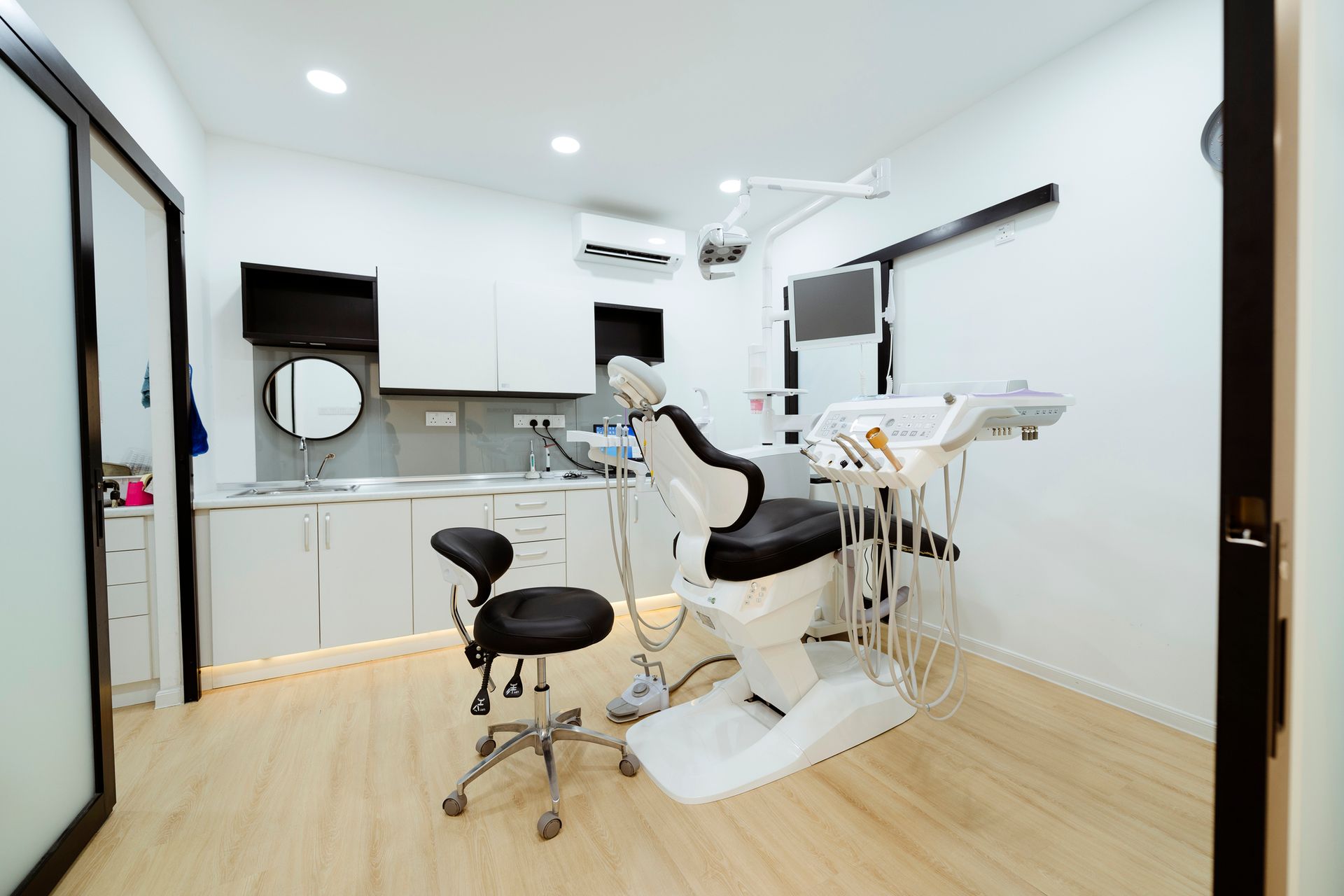 Dental clinic interior with chair, instruments, cabinets, and sink.