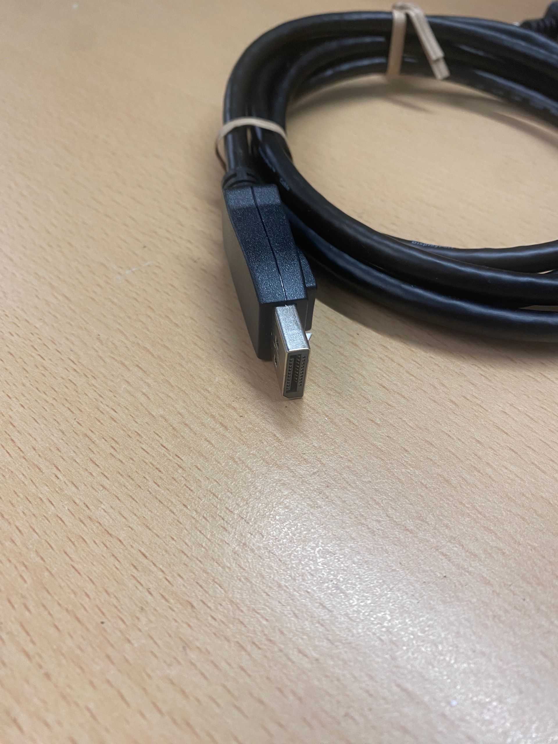 Black coiled USB cable with a tag, on a light brown surface.