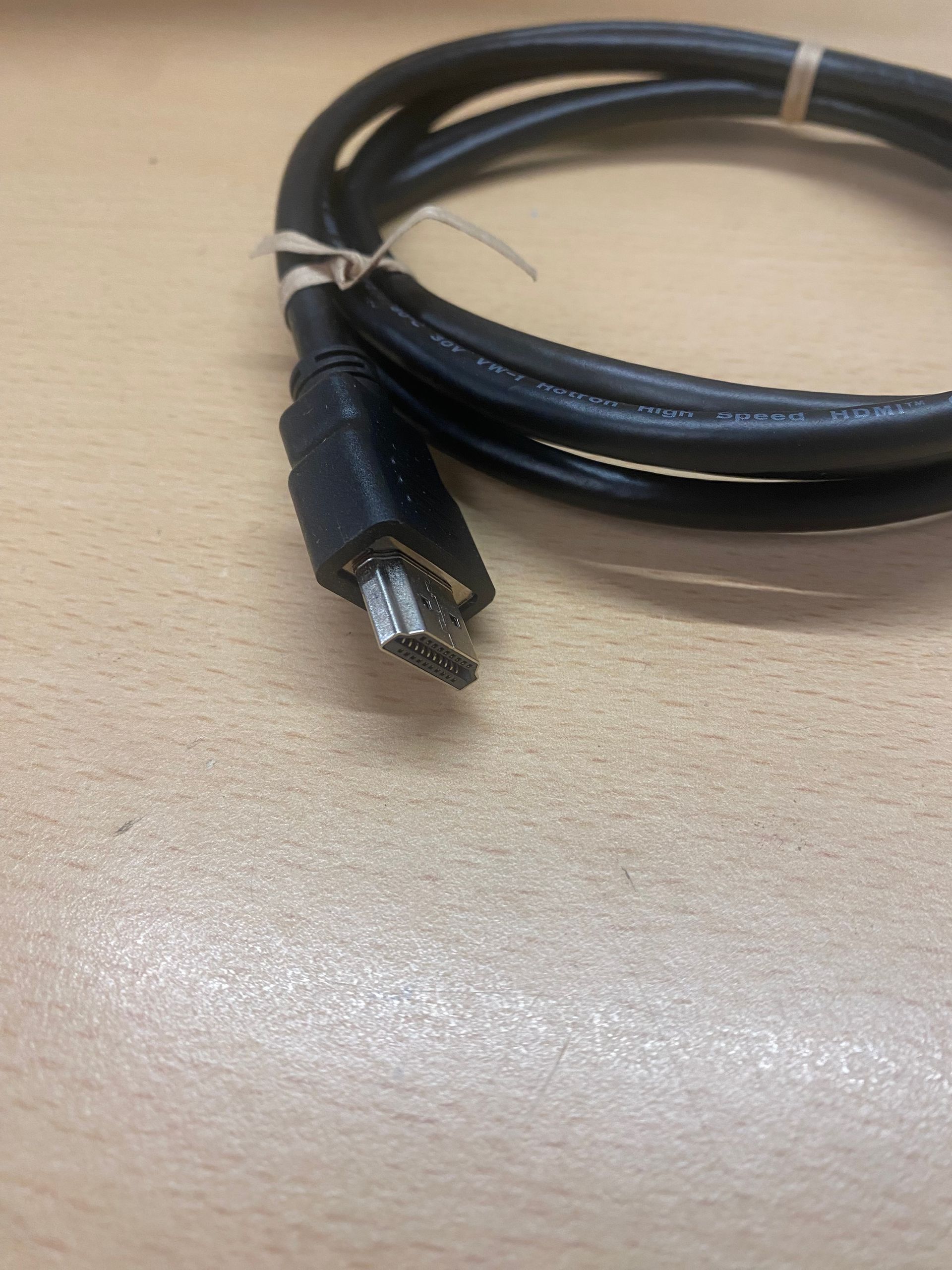 Black data cable coiled on a light brown surface.