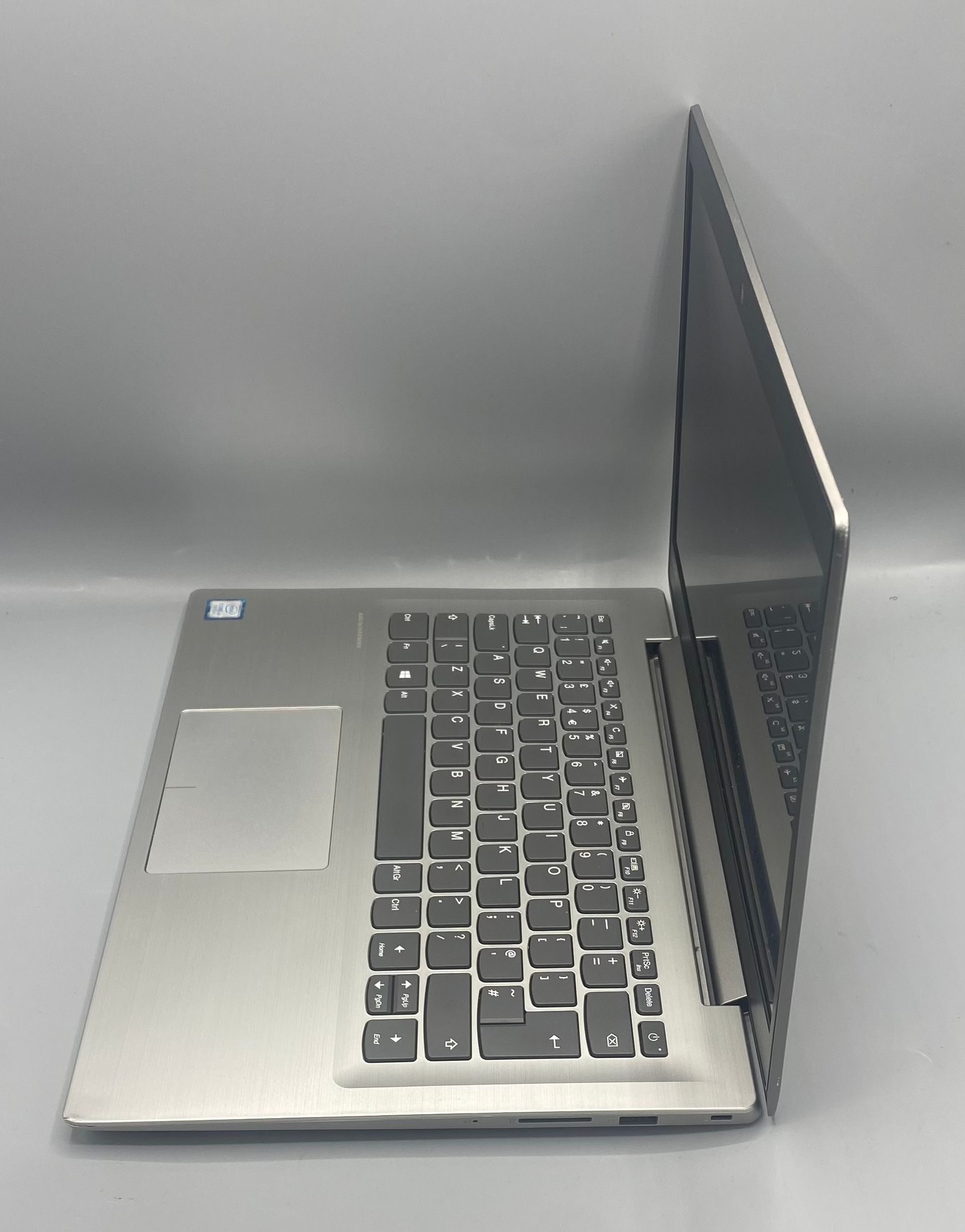 Open Lenovo laptop on a gray surface with time displayed on the screen.