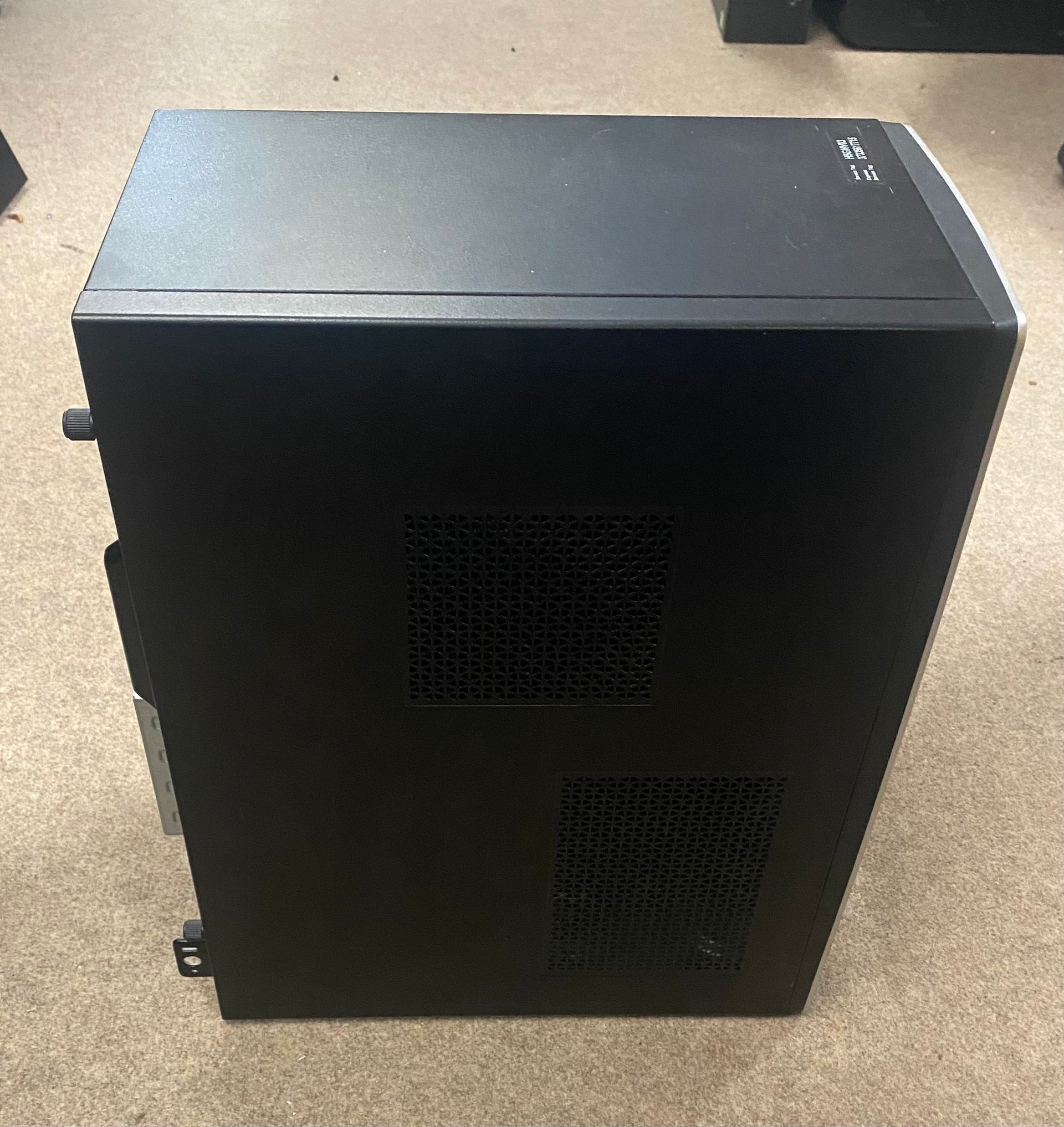 Black Dell desktop computer on a tan carpet.