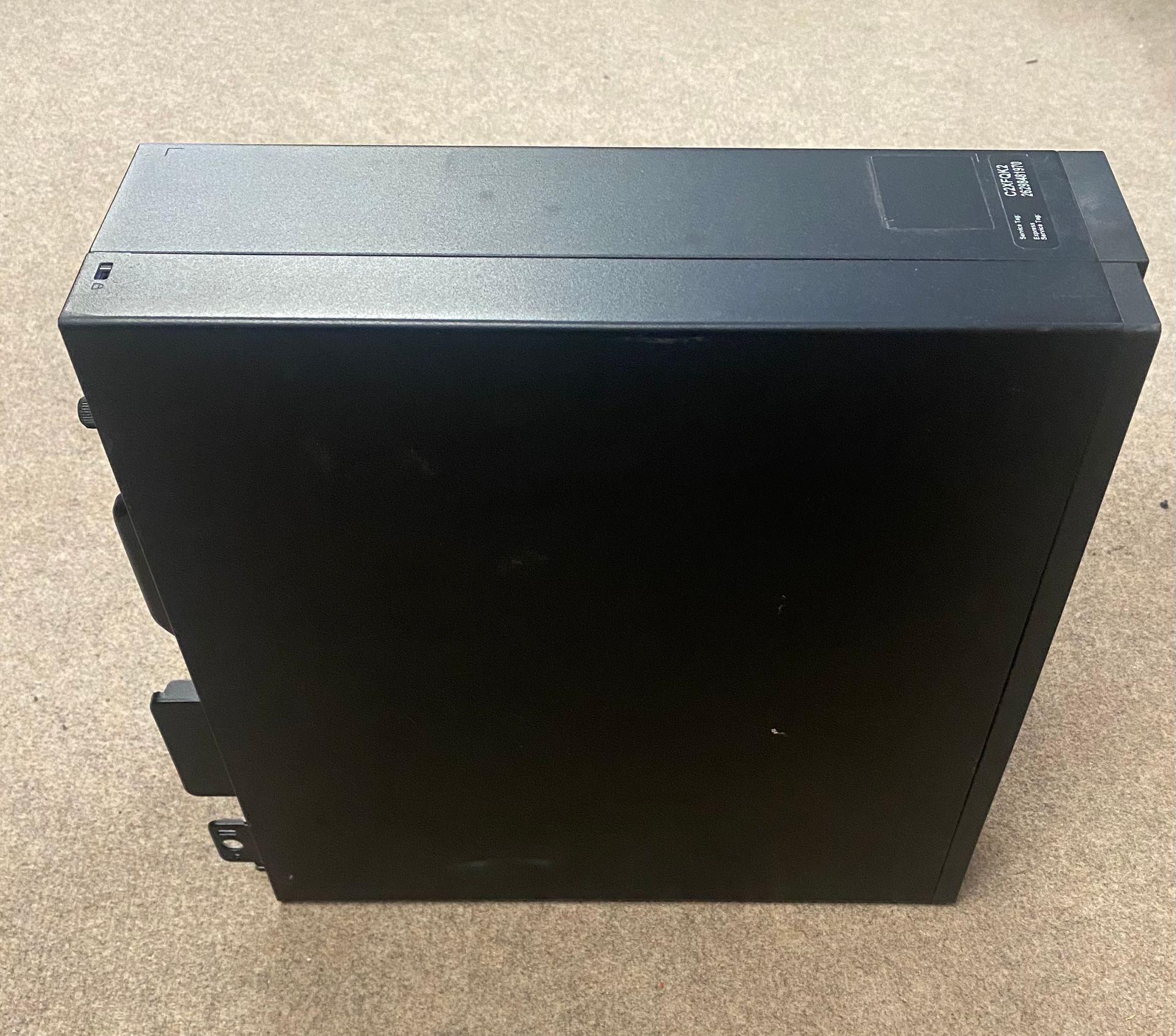 A black Dell computer tower on a beige carpet.