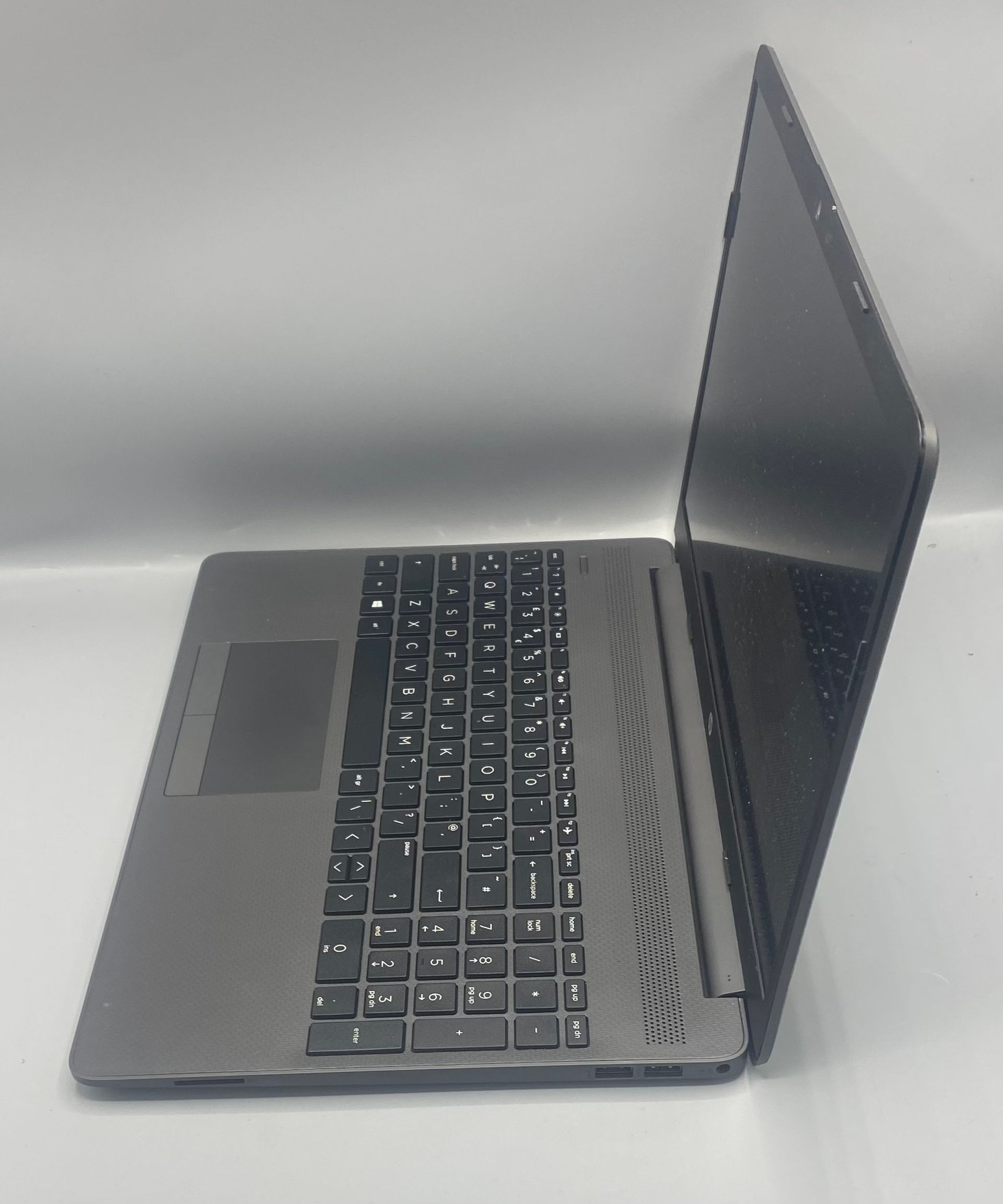 Gray HP laptop displaying a blue abstract background, open on a white surface.