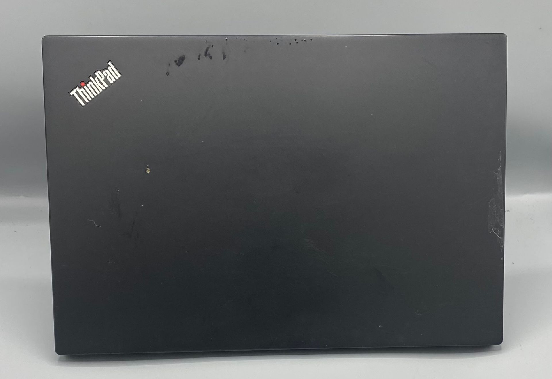 Black Lenovo ThinkPad laptop with Windows 11 desktop open on a white surface.