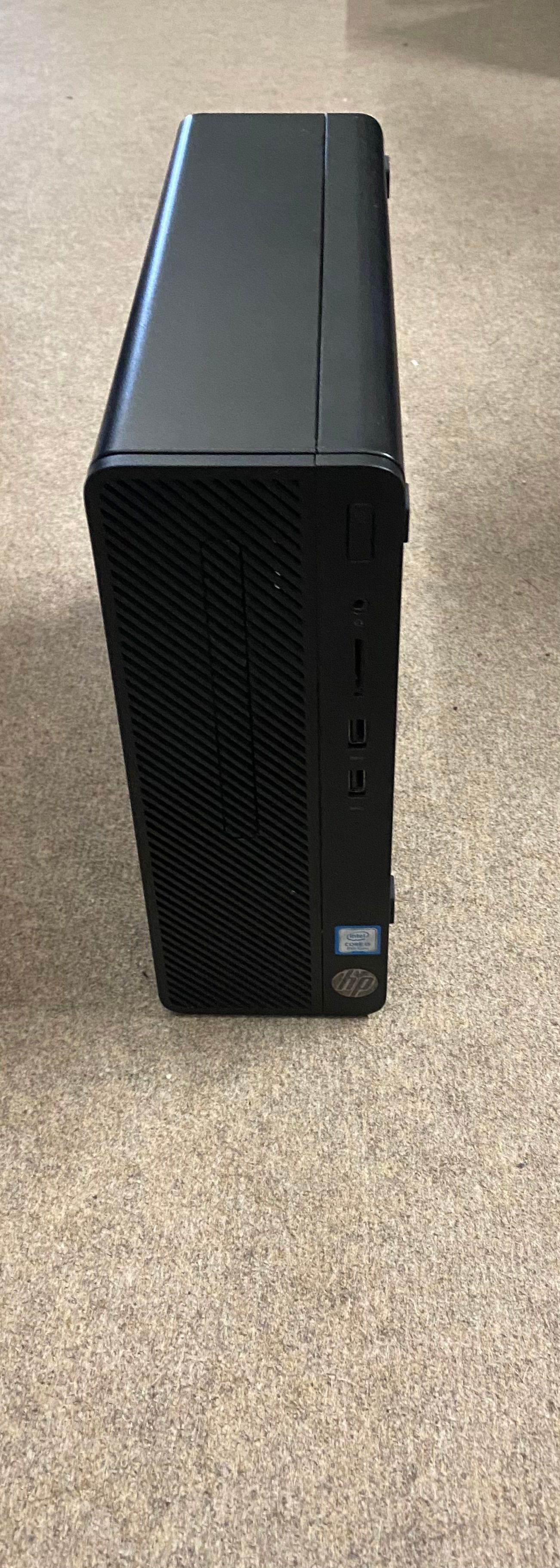 Black desktop computer on a neutral-colored floor. Front shows ports and Intel sticker.