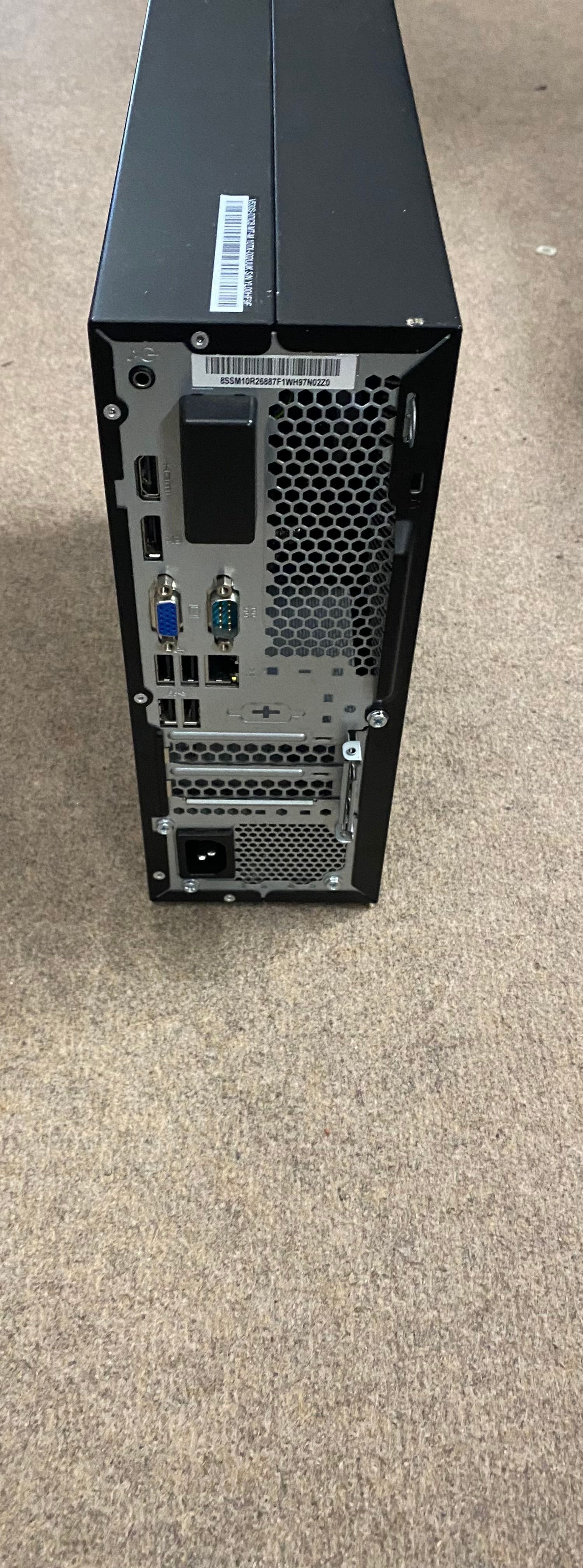 Black desktop computer tower on a beige carpet. The Lenovo logo is visible.