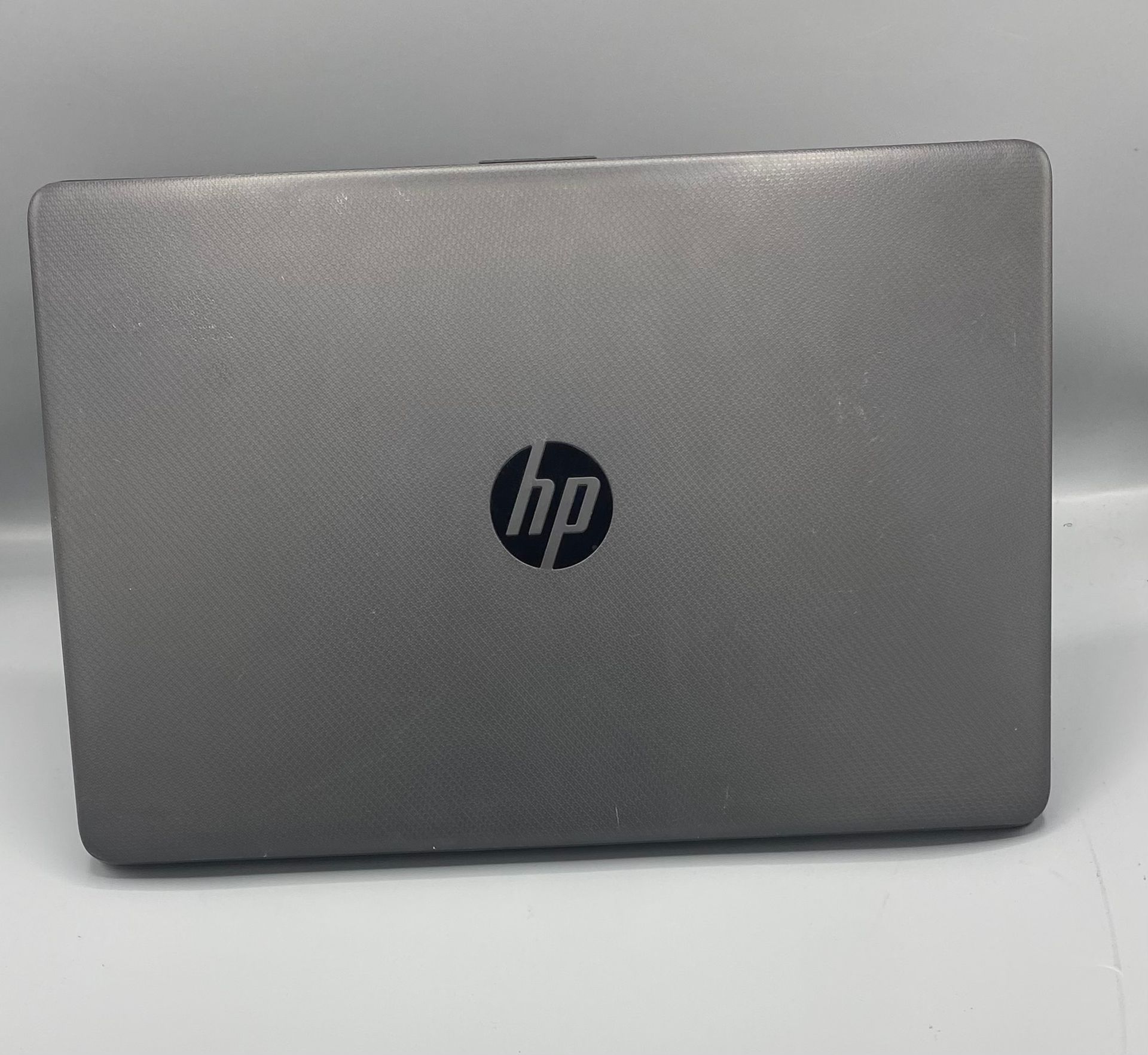 Gray HP laptop open on a white surface, displaying a landscape on its screen.