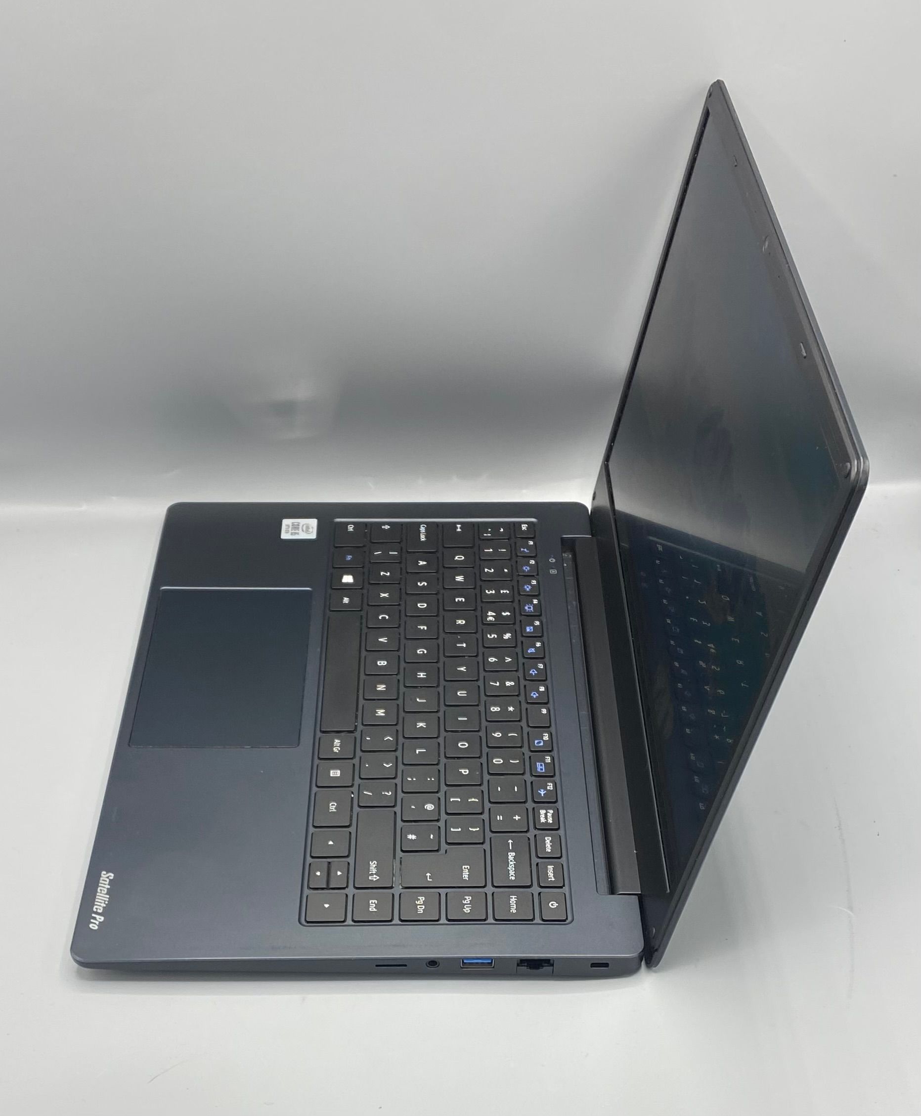 A dark gray laptop is open, displaying a scenic blue lake and mountain background.