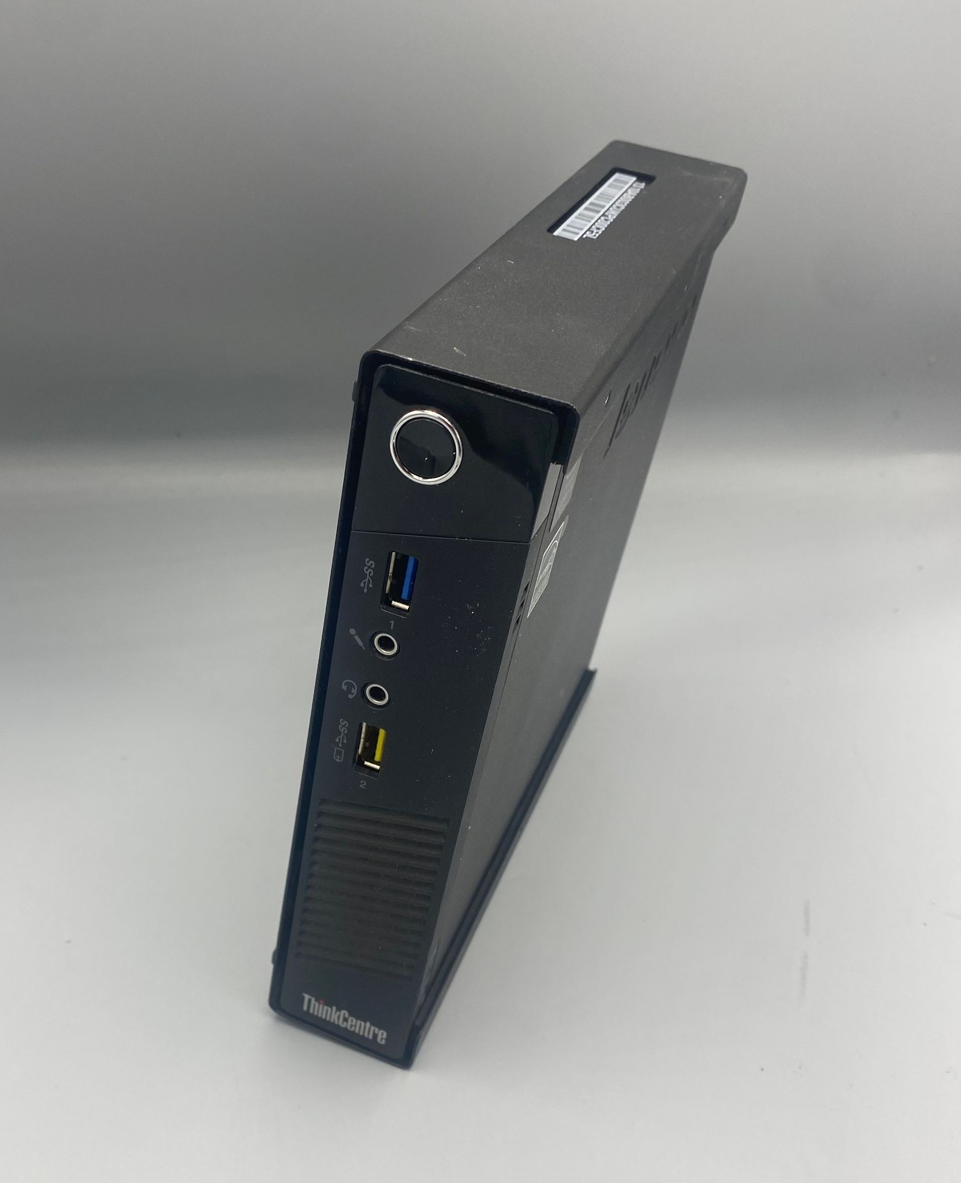 Black Lenovo ThinkCentre computer on a white surface, front view.