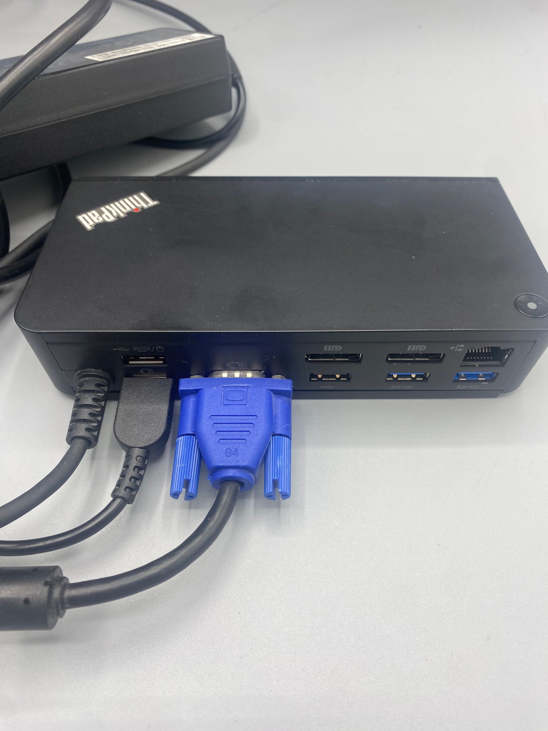 Black ThinkPad docking station with attached cables and ports: power, HDMI, and VGA.